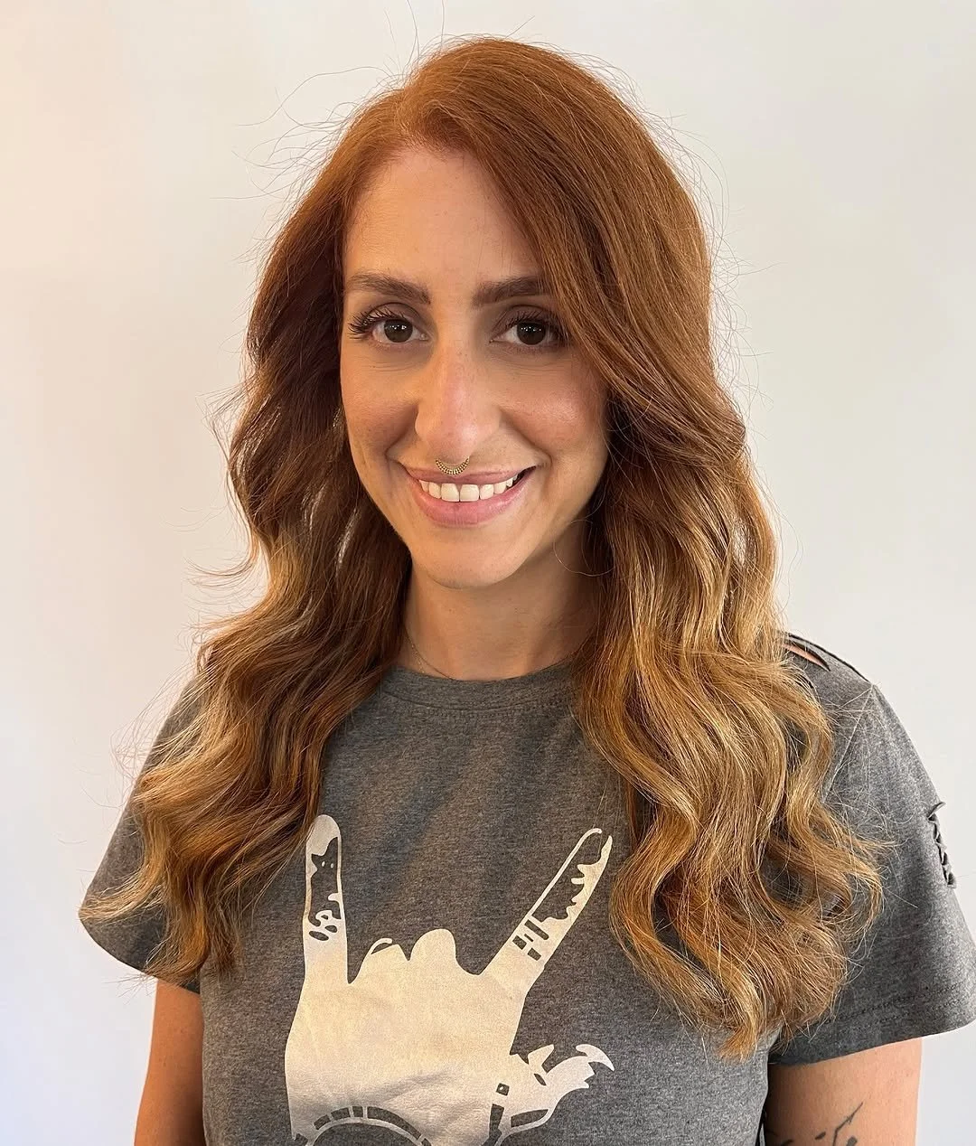  Woman with warm copper balayage and soft waves, showcasing a dimensional color transformation by TEAL Hair &amp; Makeup Studio. 