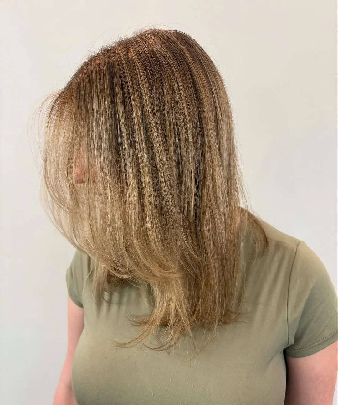  Medium-length layered blonde hair with soft highlights and face-framing layers, styled smooth by Teal Hair and Makeup Studio. 