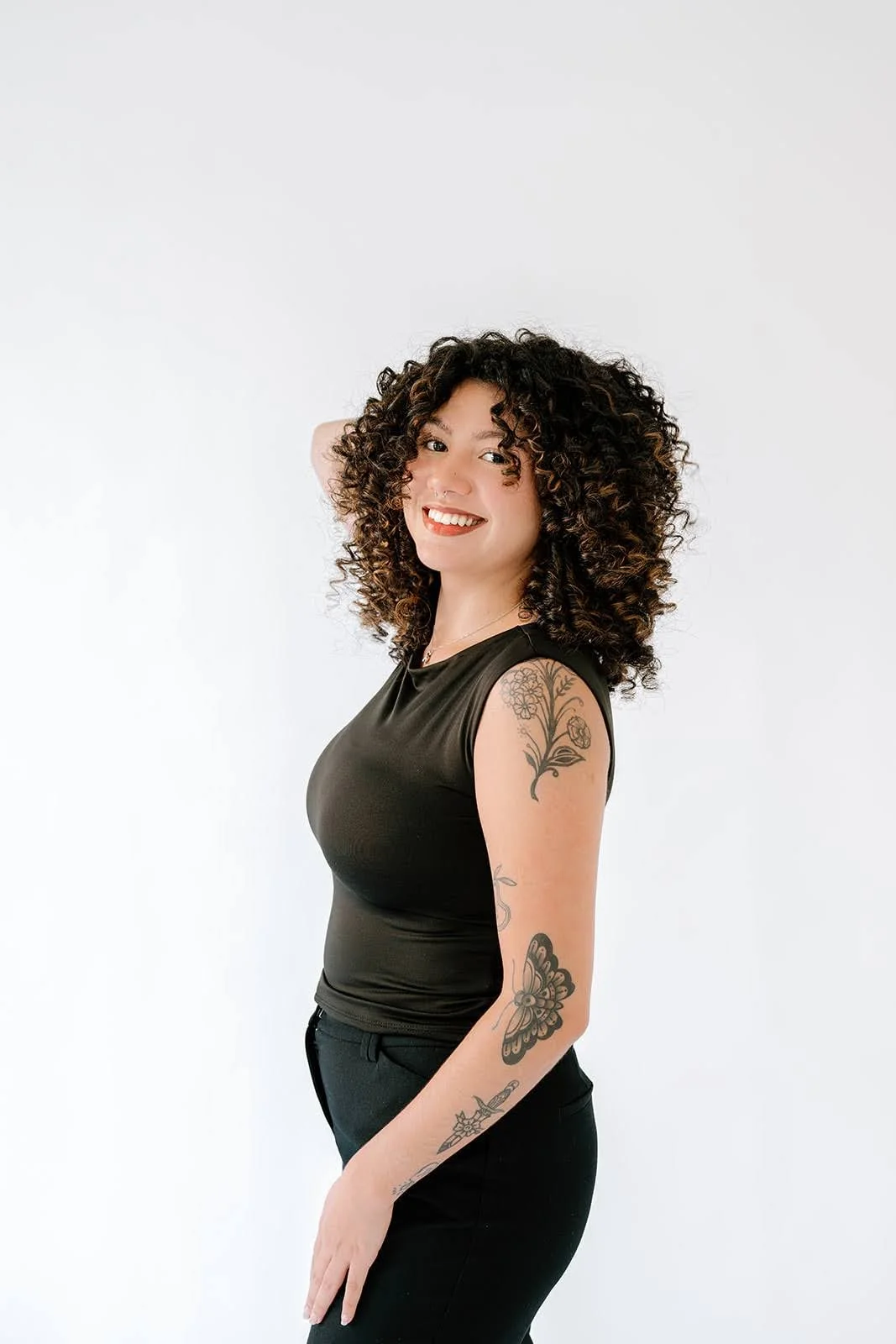 Alliyah, Teal Studio Level 1 stylist specializing in curls and lived-in color, smiling with defined natural curls
