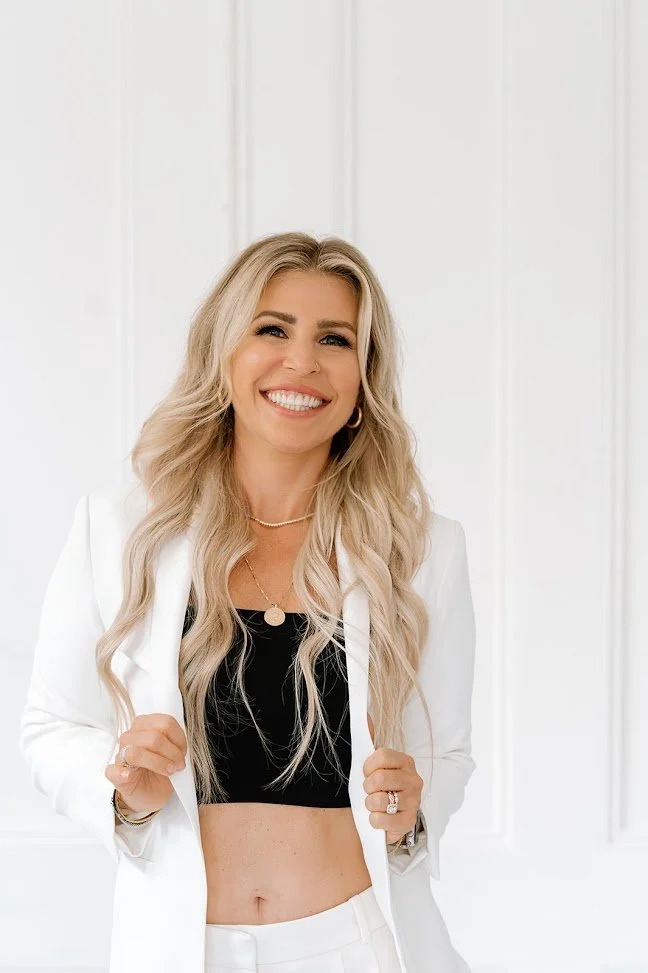 Christina Truscello, Teal Studio owner and hair extension specialist, smiling in a white suit with long blonde waves