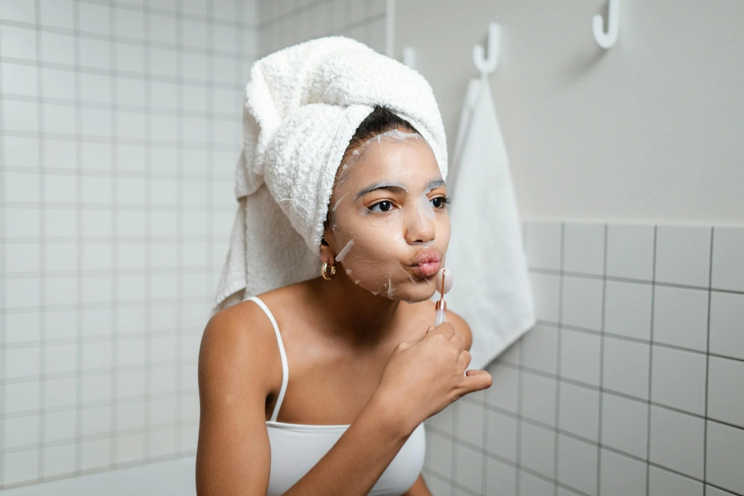 A woman applies a targeted skincare treatment in her bathroom, reflecting advanced treatments like peels and facials used three to six months before a wedding to improve skin tone and texture.
