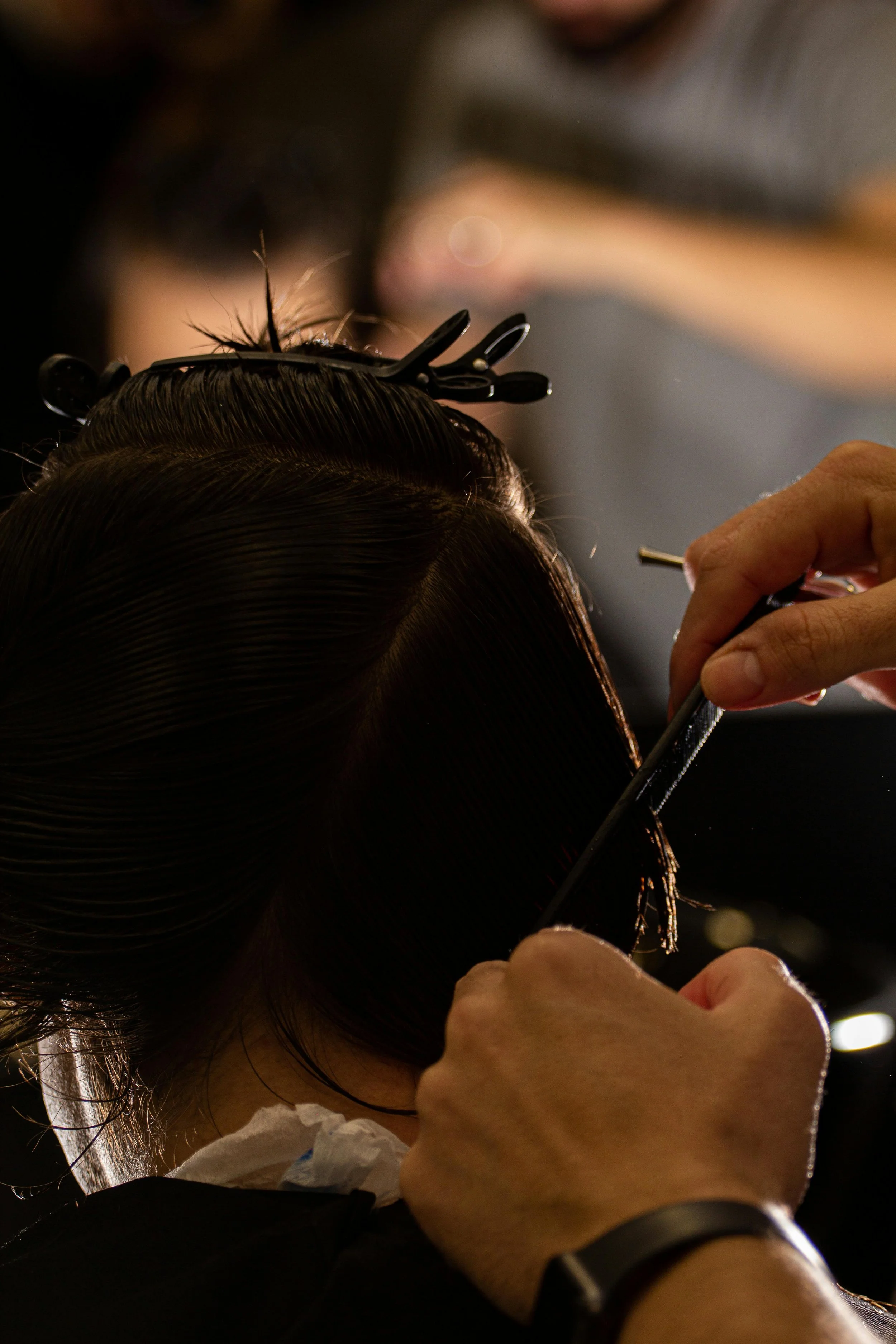 Stylist applying hair extensions to a client’s hair using professional salon tools.