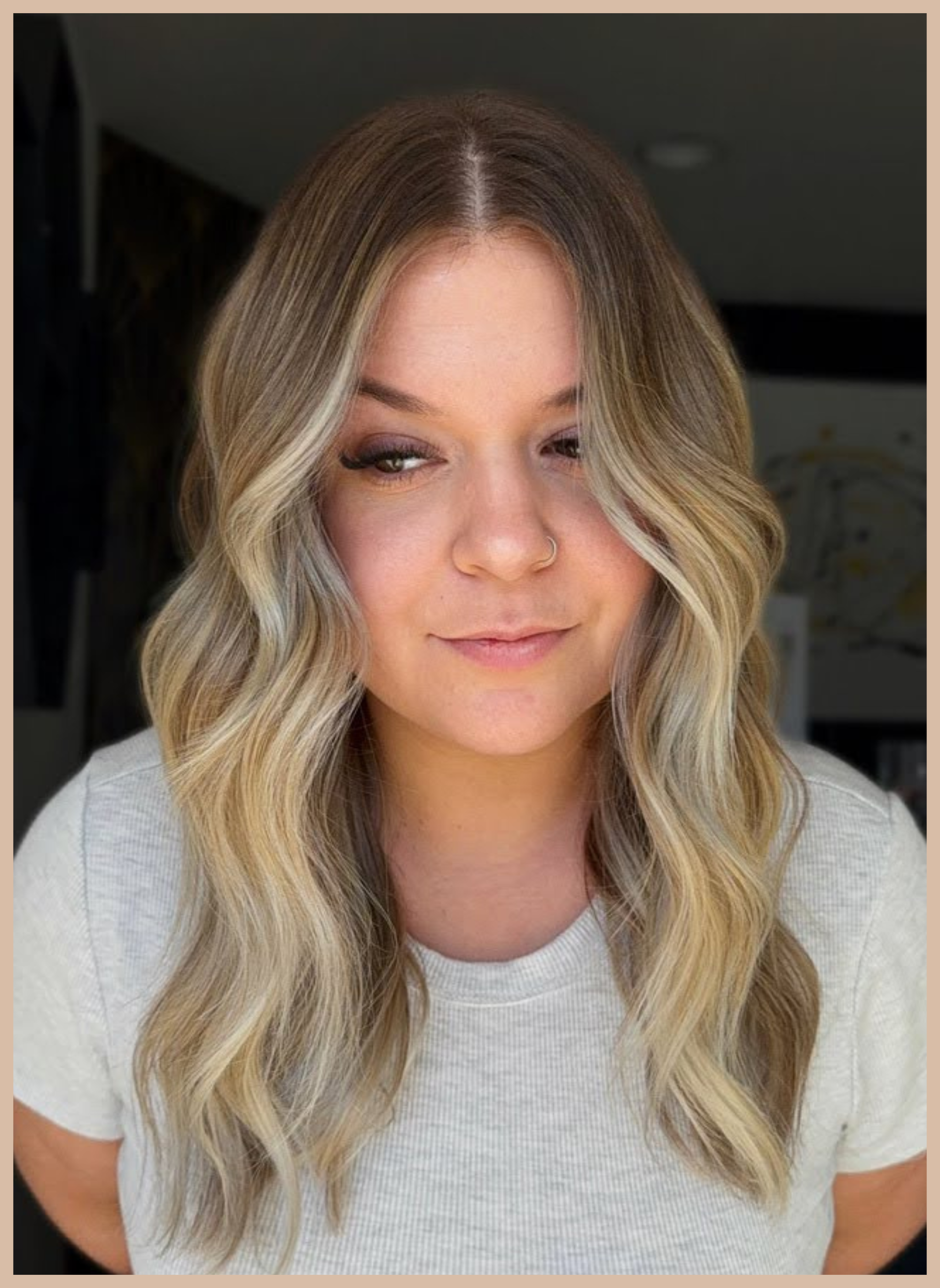 A client with softly blended bronde hair and teddy bear blonde highlights showcases seamless hair extensions styled in loose waves at Teal Hair and Makeup Studio.