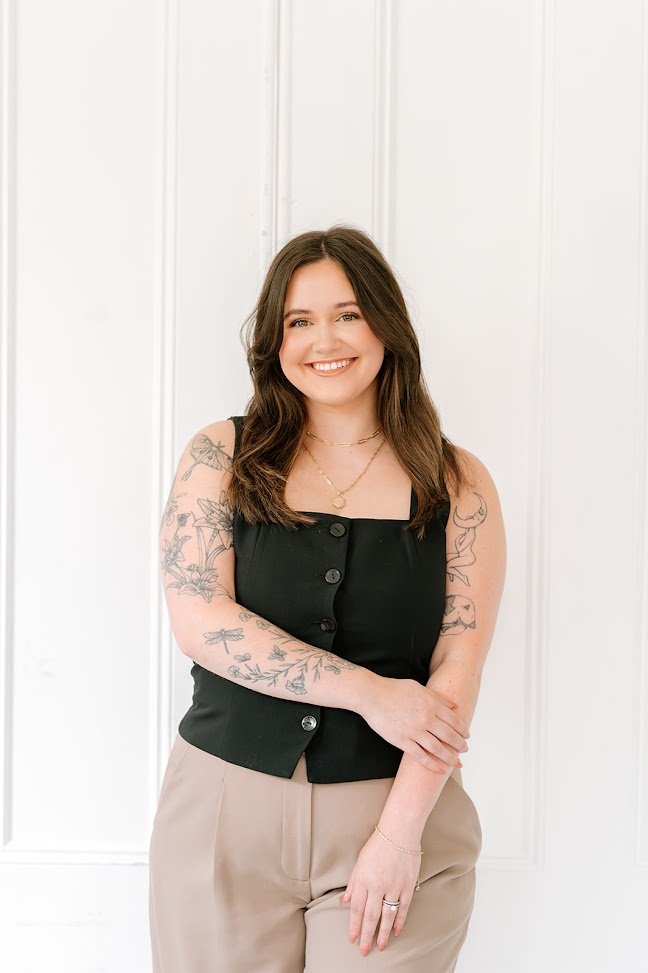 Marissa, Teal Studio Level 3 stylist and curl specialist, smiling with long brunette hair in a studio portrait