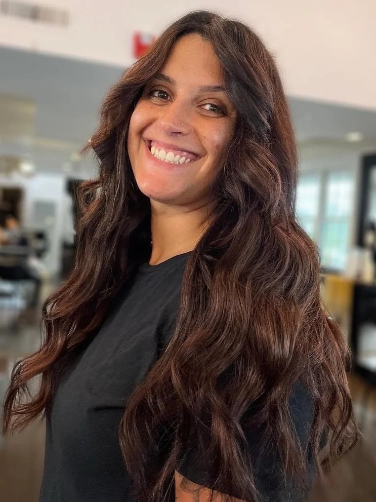 Long dark brown hair after a Hair Color Retouch, styled in soft, loose waves with a smooth finish