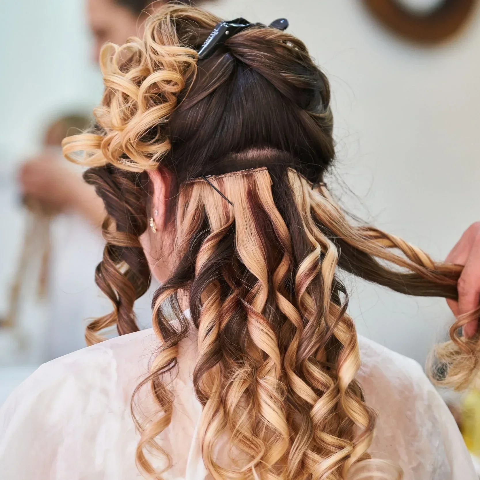 Hair extensions being installed to add length and fullness to curled hair