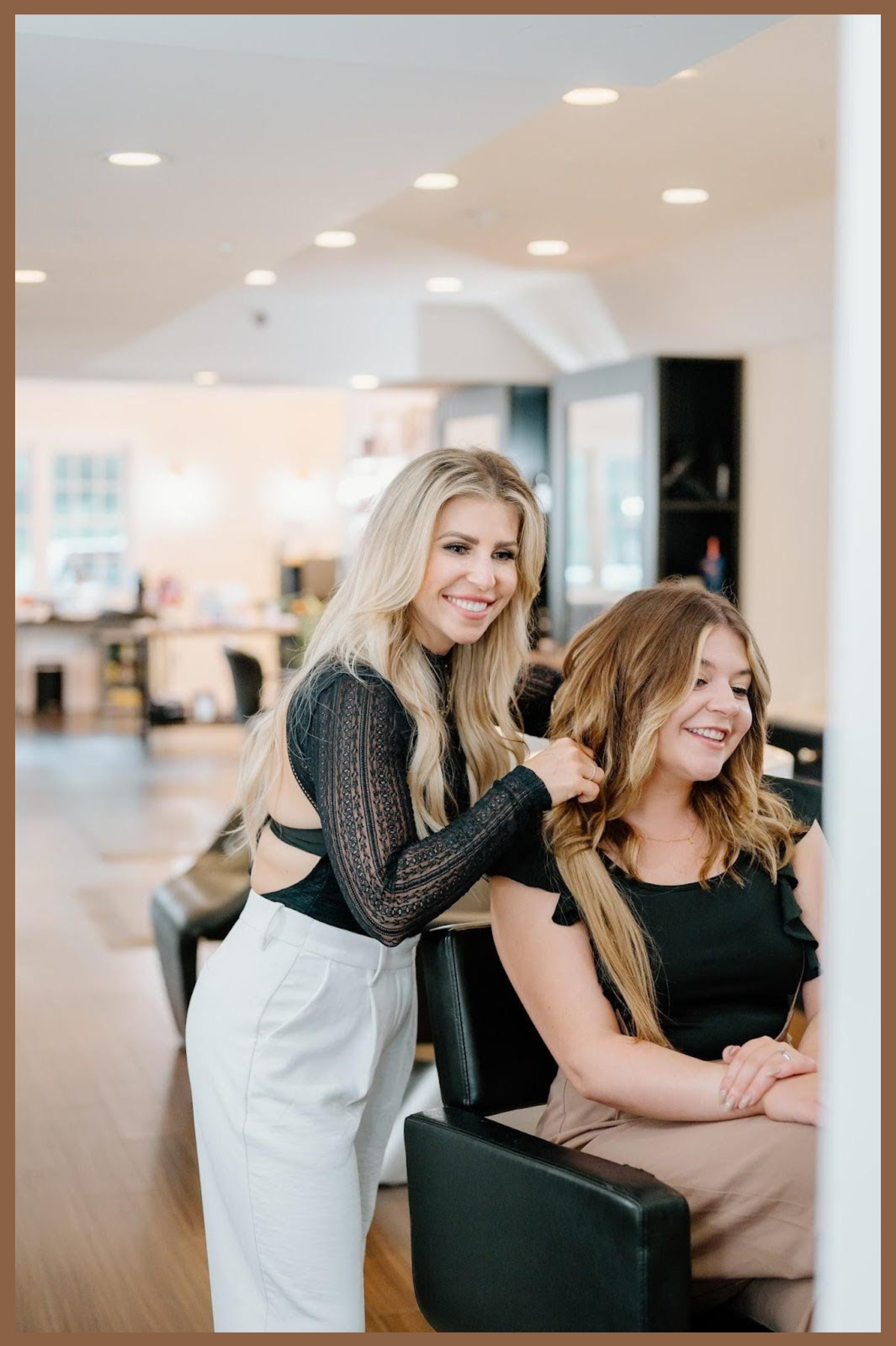 A stylist at Teal Hair and Makeup Studio installs hair extensions, creating a soft bronde hair look with teddy bear blonde tones on a smiling client.