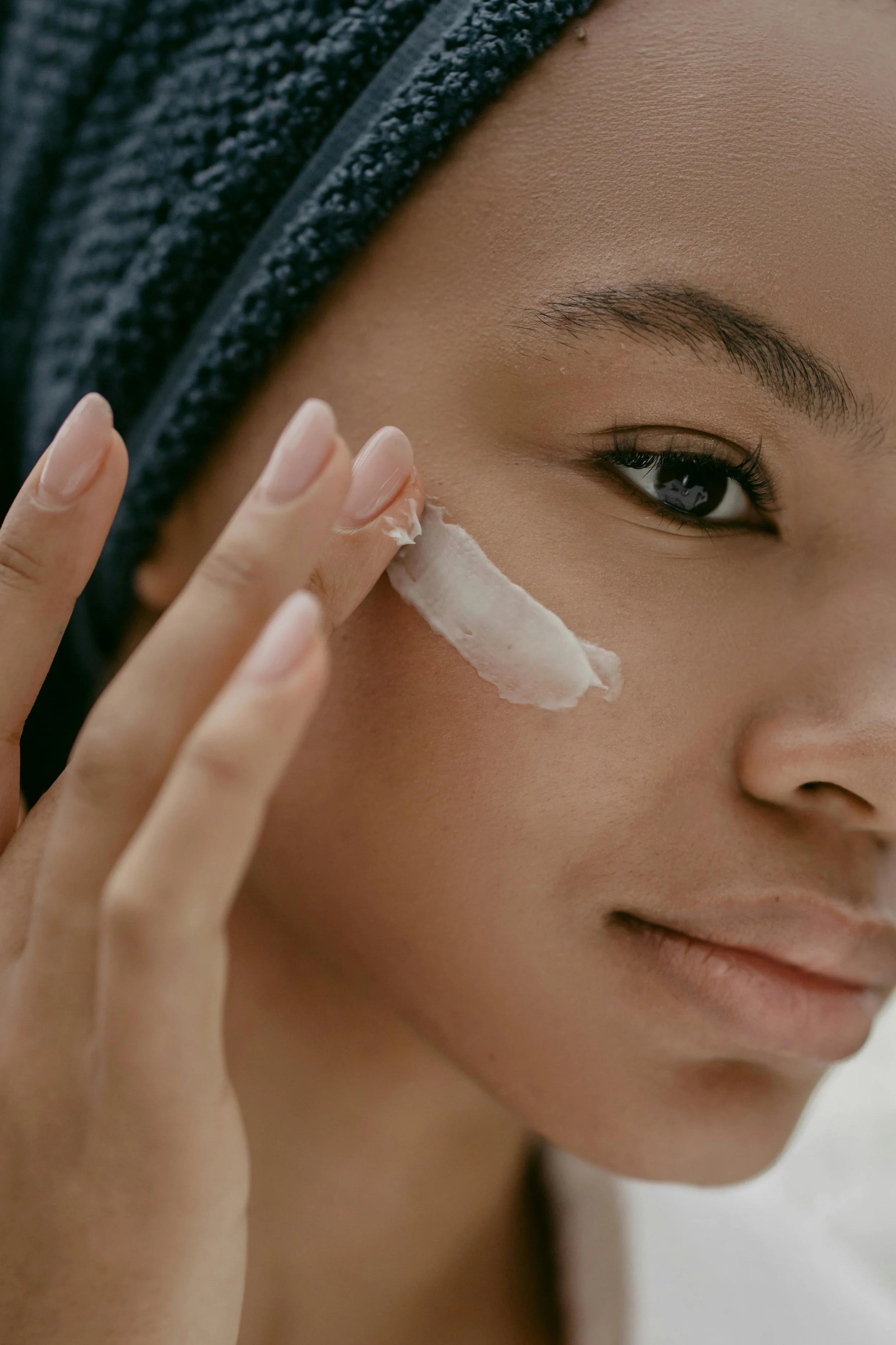A woman applies vitamin C cream to her cheek as part of a brightening skincare routine.