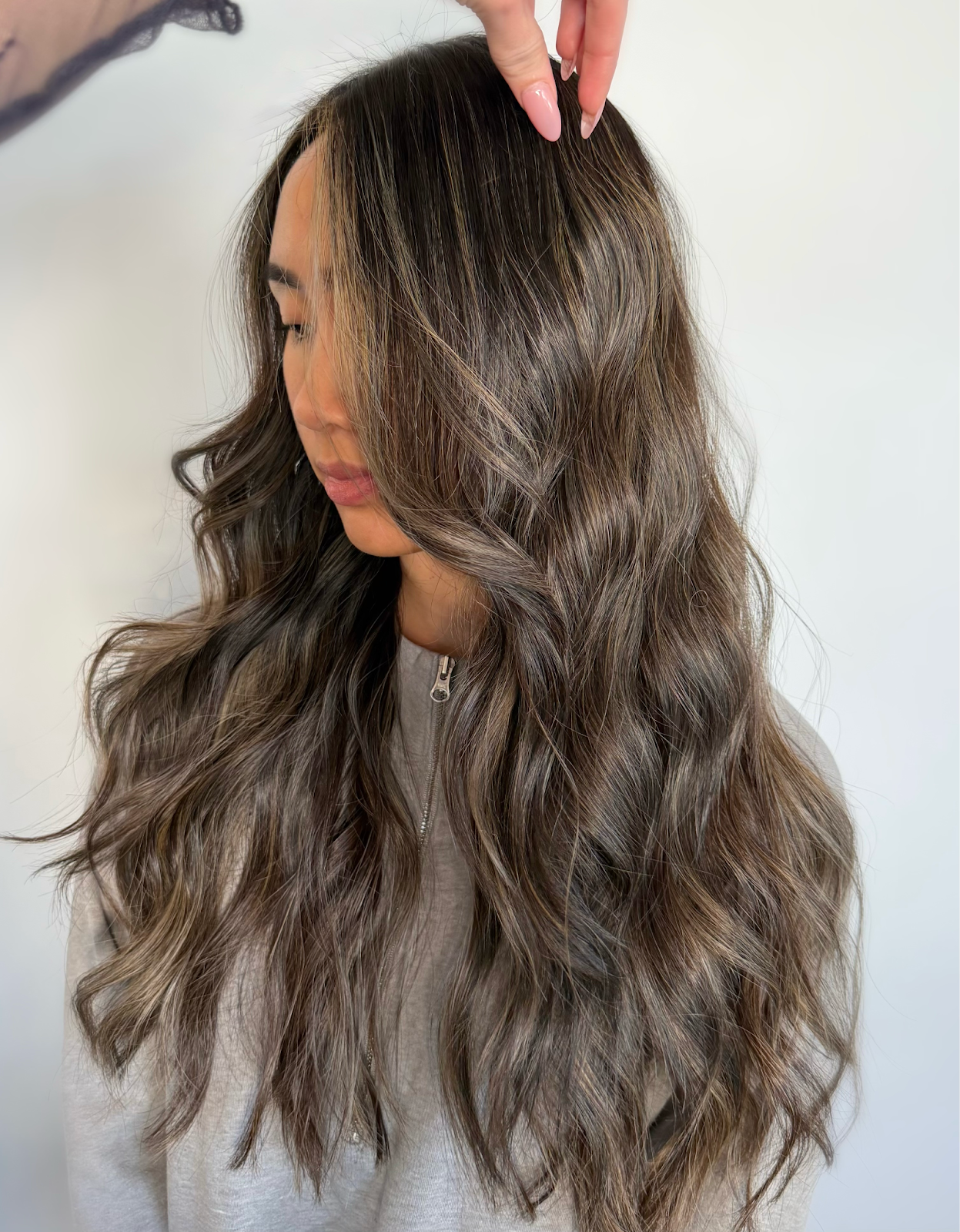 Soft, dimensional brunette hair with blended highlights from a partial lightening service, styled in loose waves at Teal Hair and Makeup Studio.