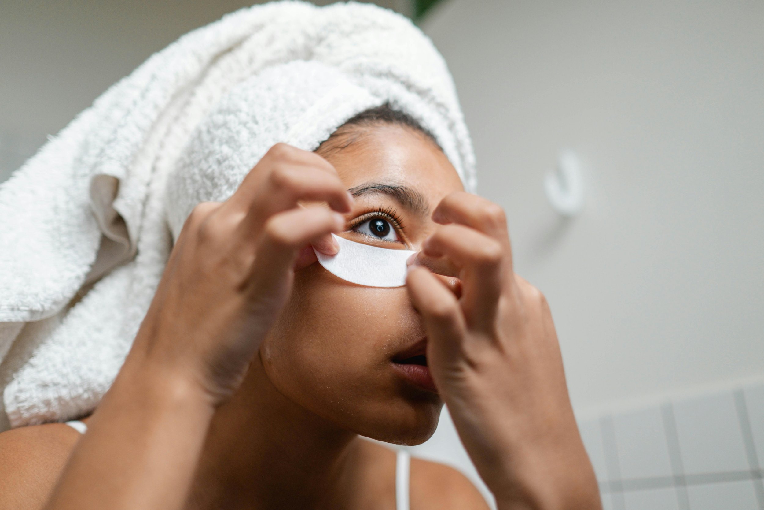 A bride applies under-eye patches as part of her final, gentle skincare routine in the month leading up to her wedding day.