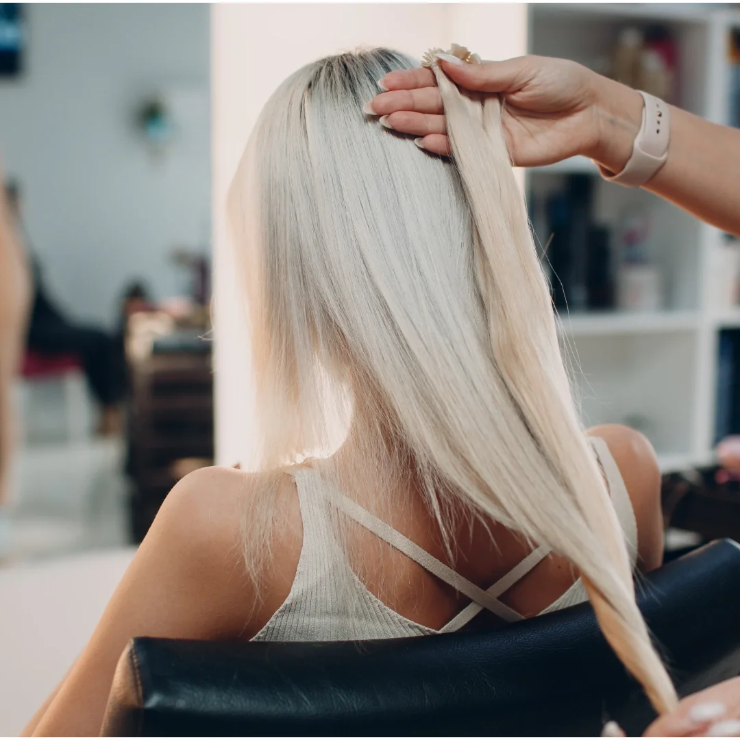Stylist working with long platinum blonde hair during a salon extension consultation
