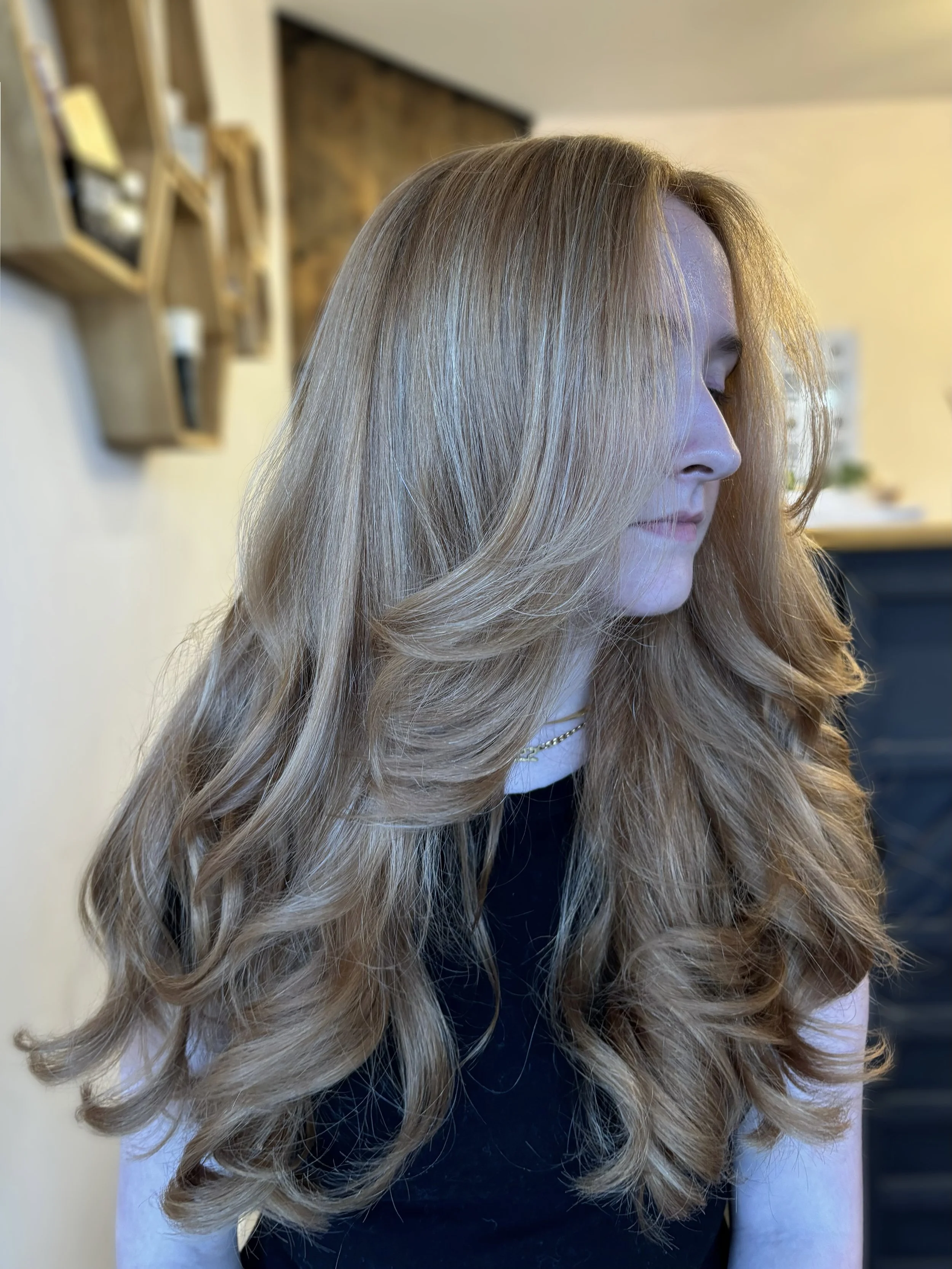 Accurately describes the visible blonde color, long layered cut, face-framing pieces, and soft curled styling.