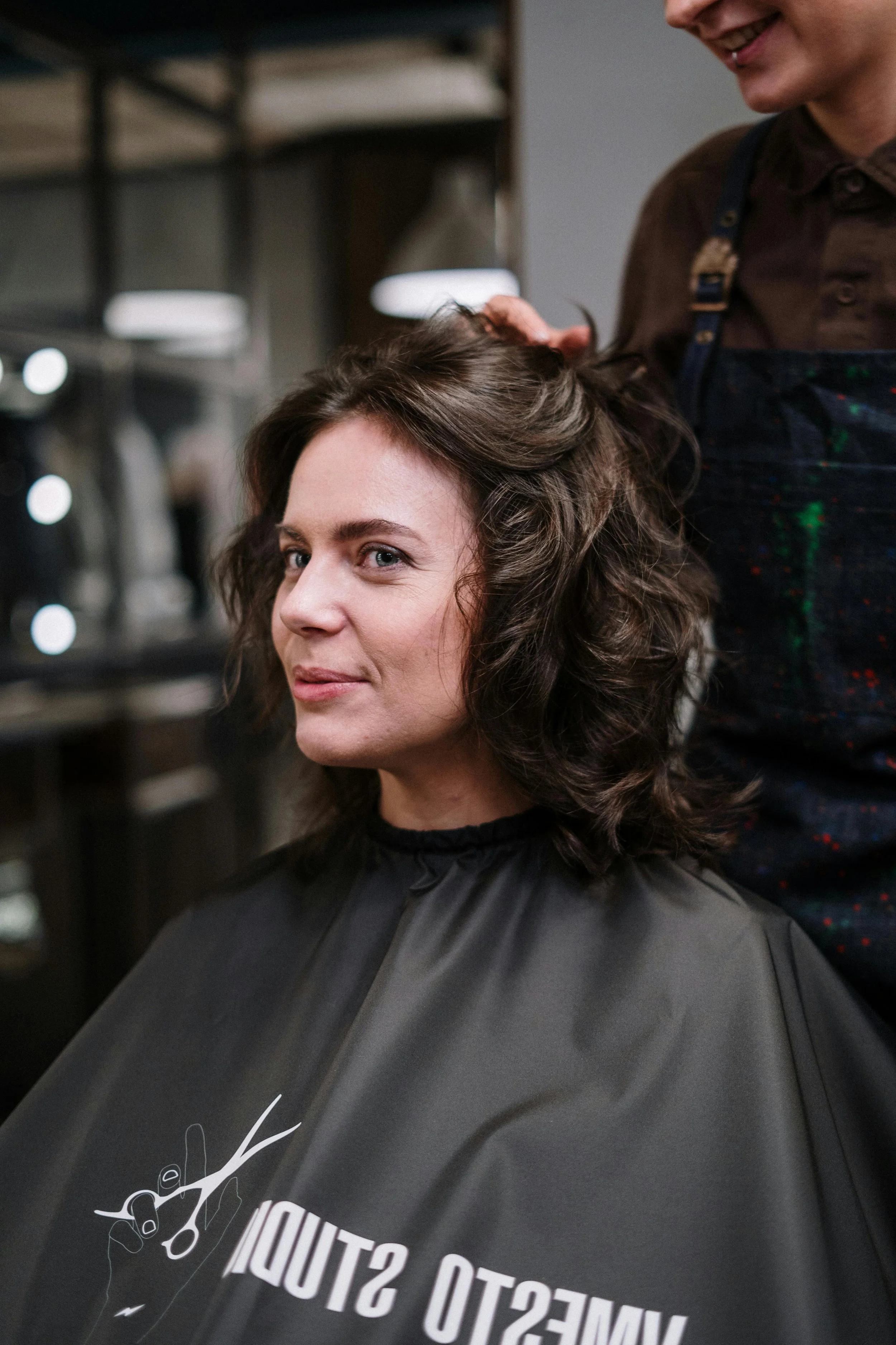 Stylist examining and shaping a client’s natural curls during a professional curly haircut at a salon.