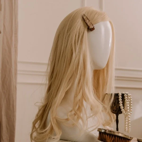 Long blonde hair topper displayed on a mannequin head with a clip securing the hair near the crown.