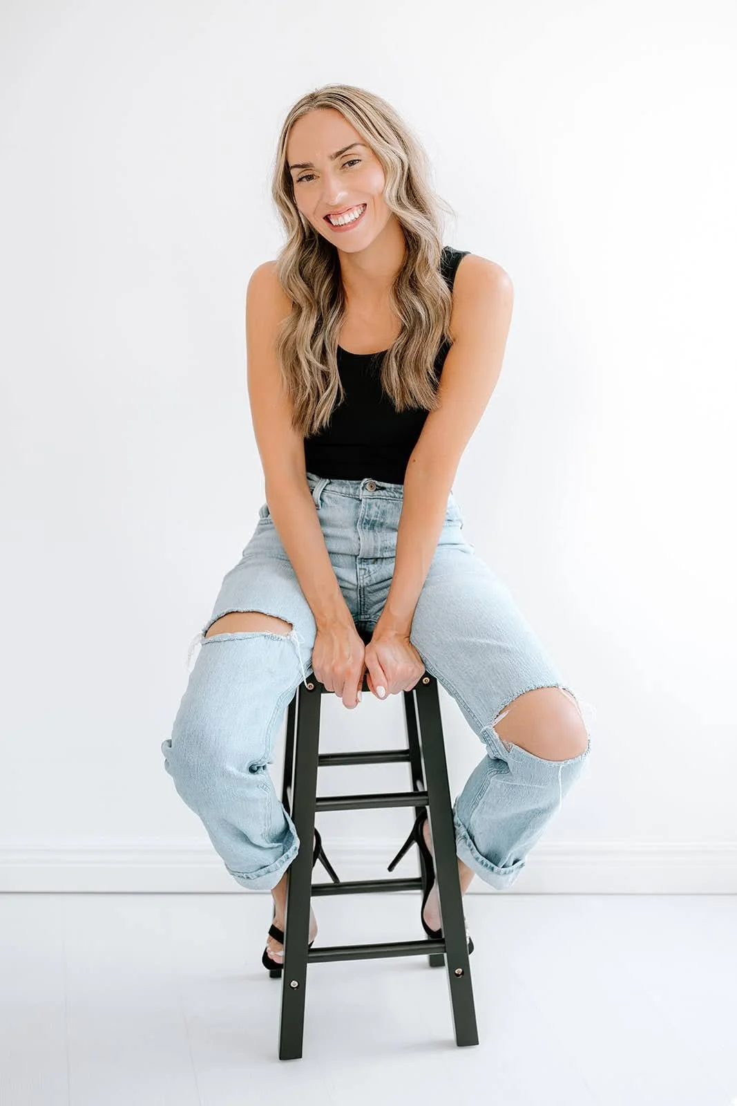 Lydia Deyle, Teal Studio hair and makeup artist and bridal specialist, smiling while seated with long blonde waves