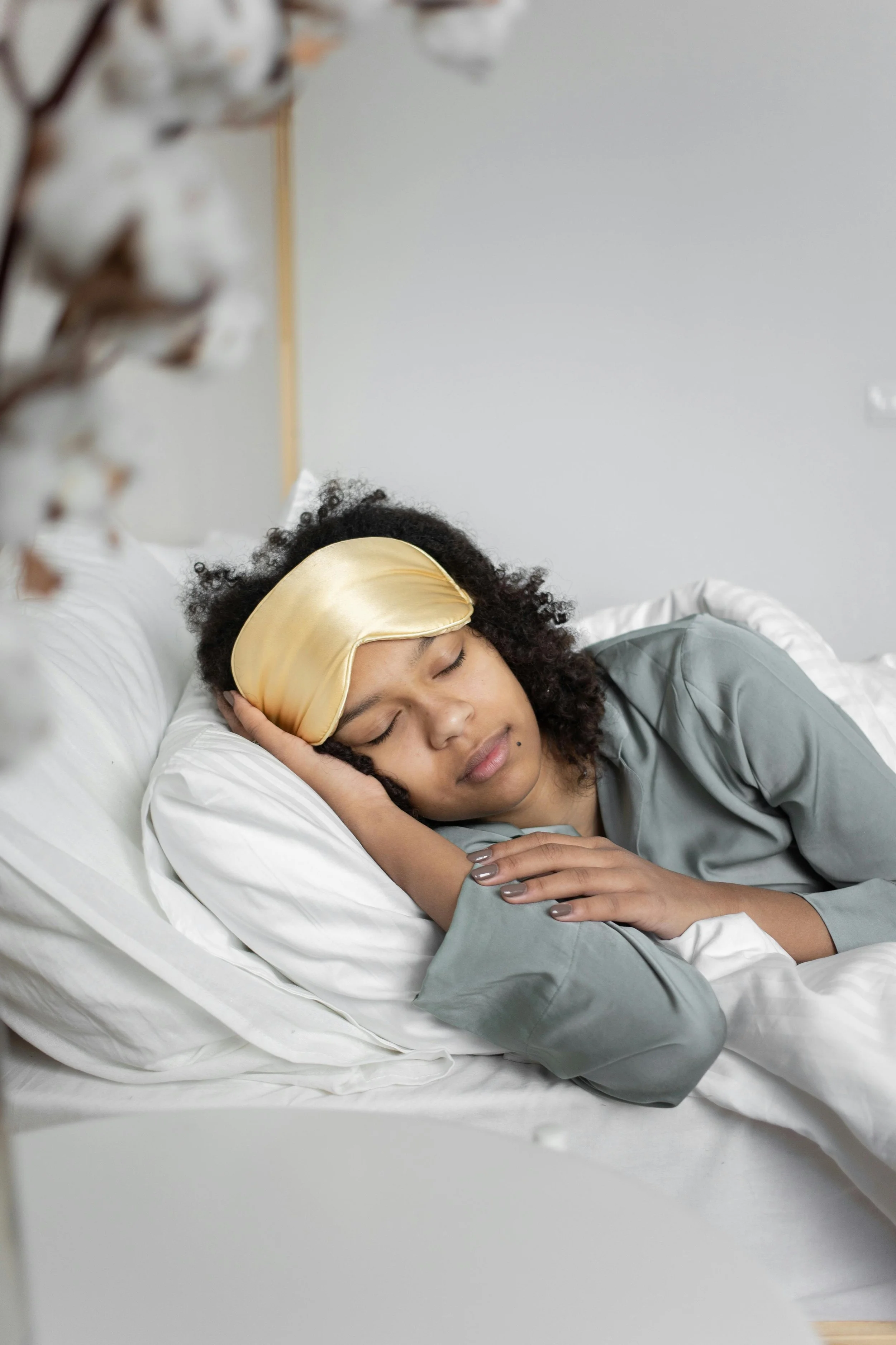 Woman sleeping peacefully while wearing a satin bonnet to protect hair and support scalp health overnight.