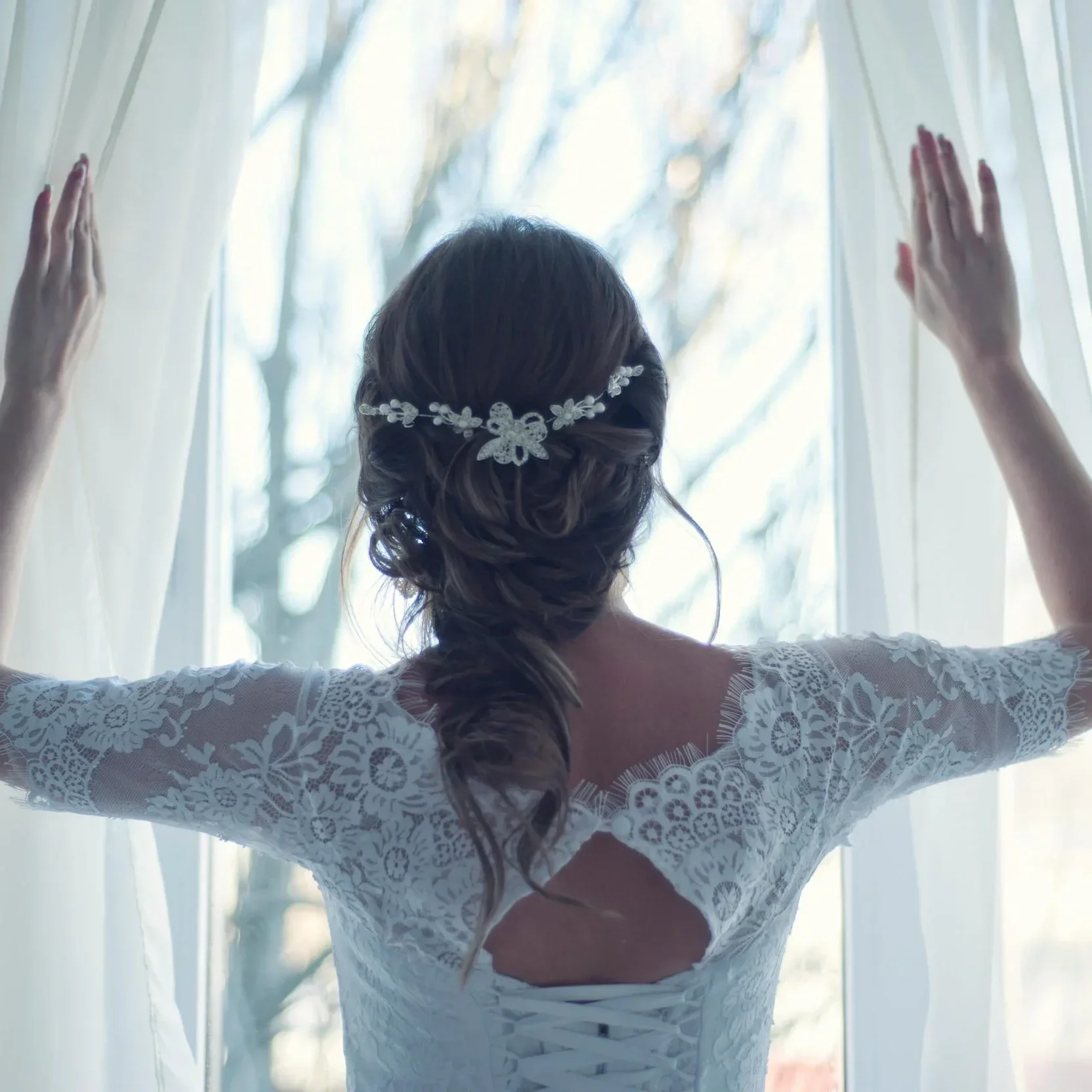 Bride in a lace wedding gown wearing an elegant low bridal updo with a floral hair accessory