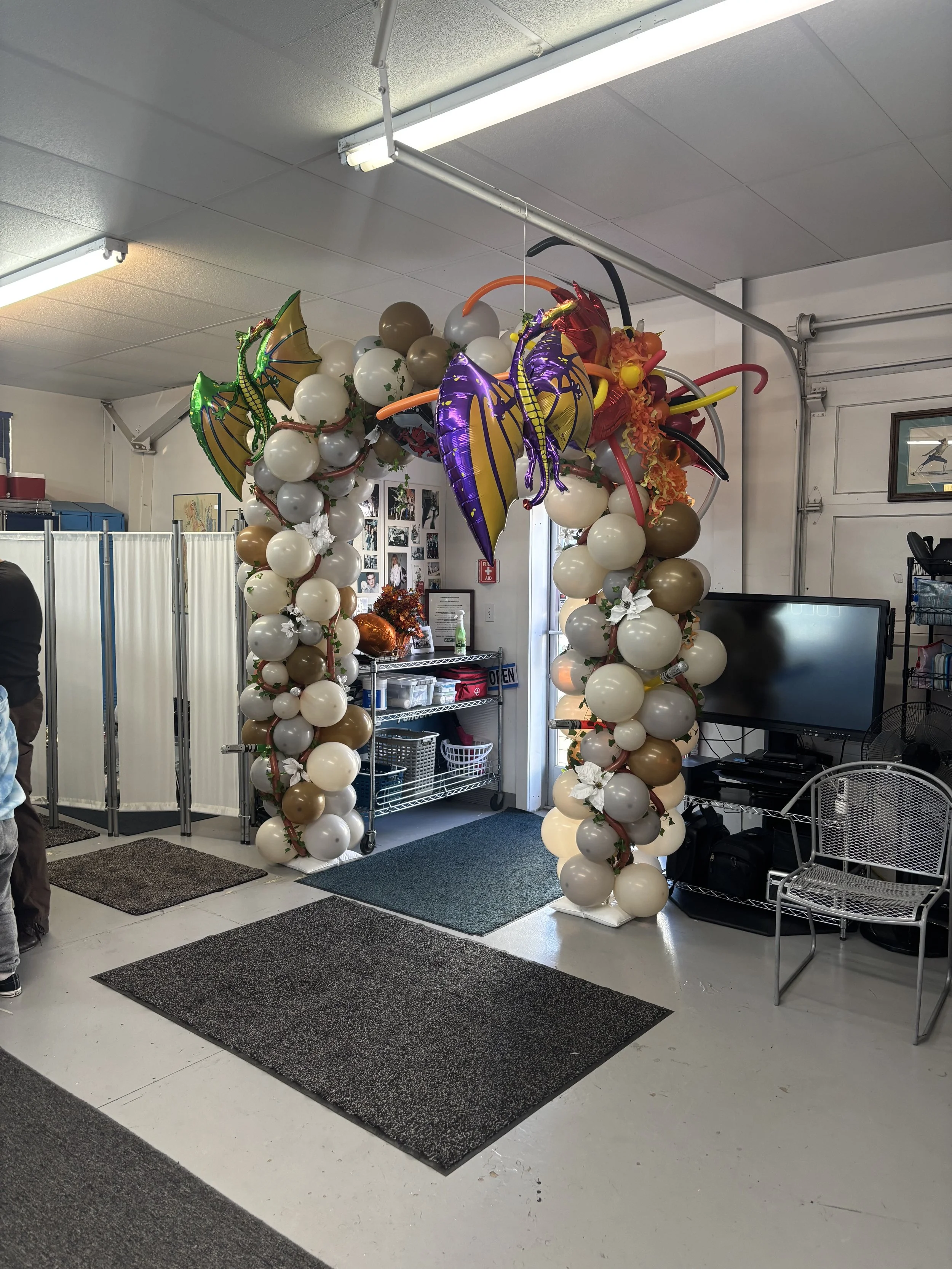 Decorative balloon arch with colorful dragon and butterfly balloons in a room.