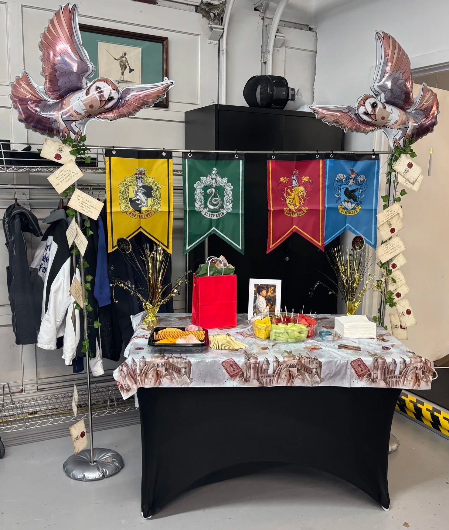 Harry Potter themed birthday party setup with Hogwarts house banners, balloons, snacks, birthday cake, and Harry Potter photo frame.