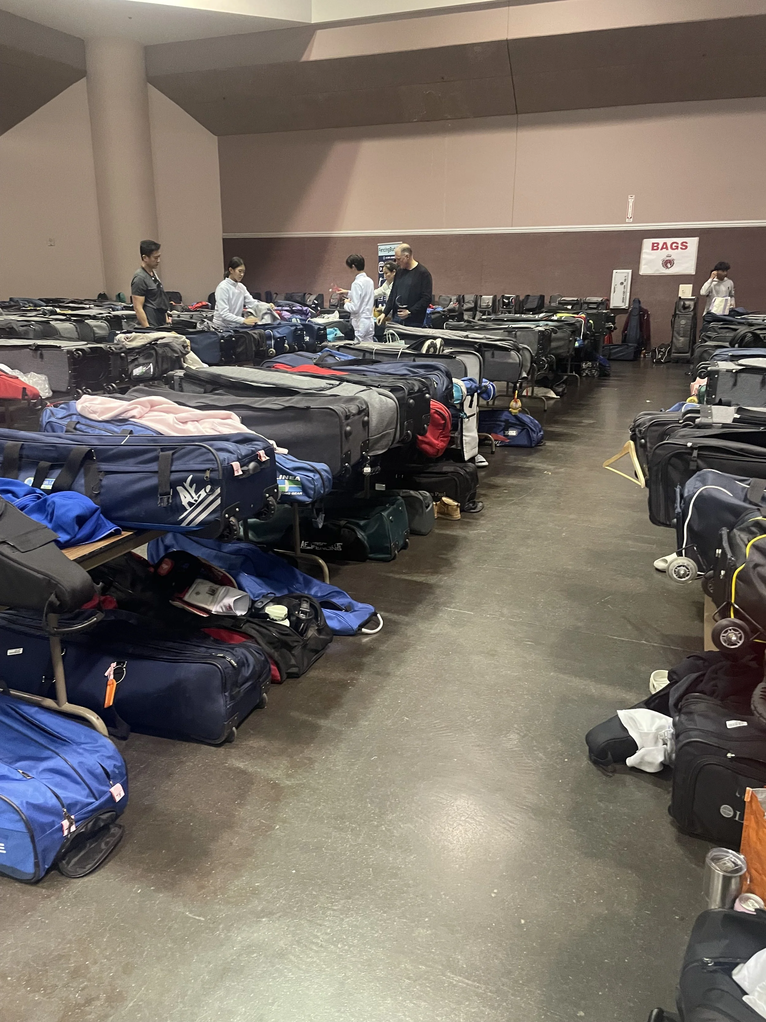 Airport baggage claim area with luggage carts filled with suitcases and bags, and people waiting.
