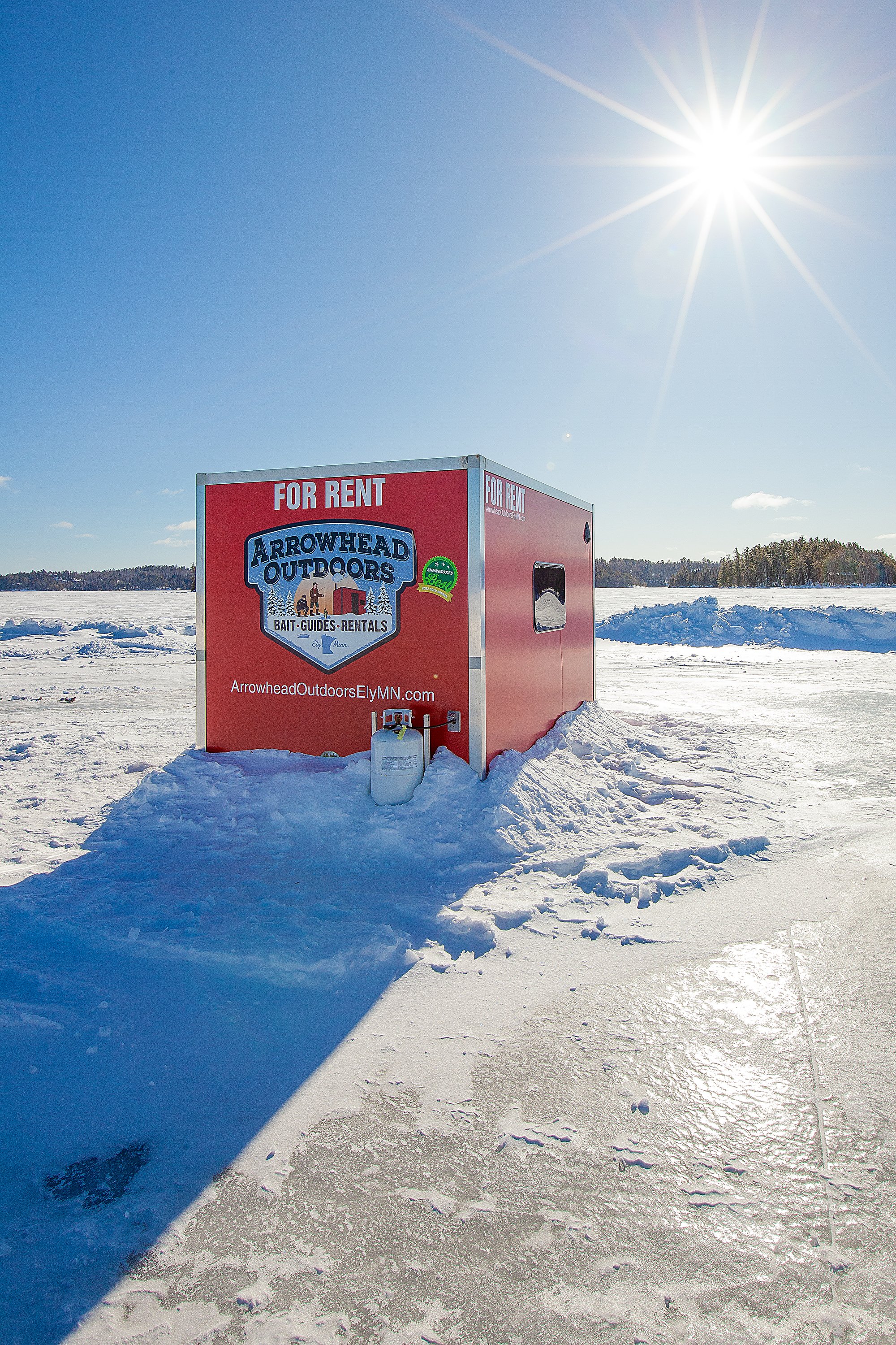 Aerial view of Arrowhead Outdoors heated ice house rental on frozen lake near Ely MN BWCA – cozy propane-heated day-use shack for walleye, pike, lake trout & more. Voted #1 bait shop in MN – book now!