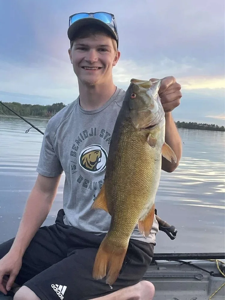 Ely MN BWCA smallmouth bass open water catch June 16 2021, young angler holding bronze smallie at sunset on boat, Arrowhead Outdoors report