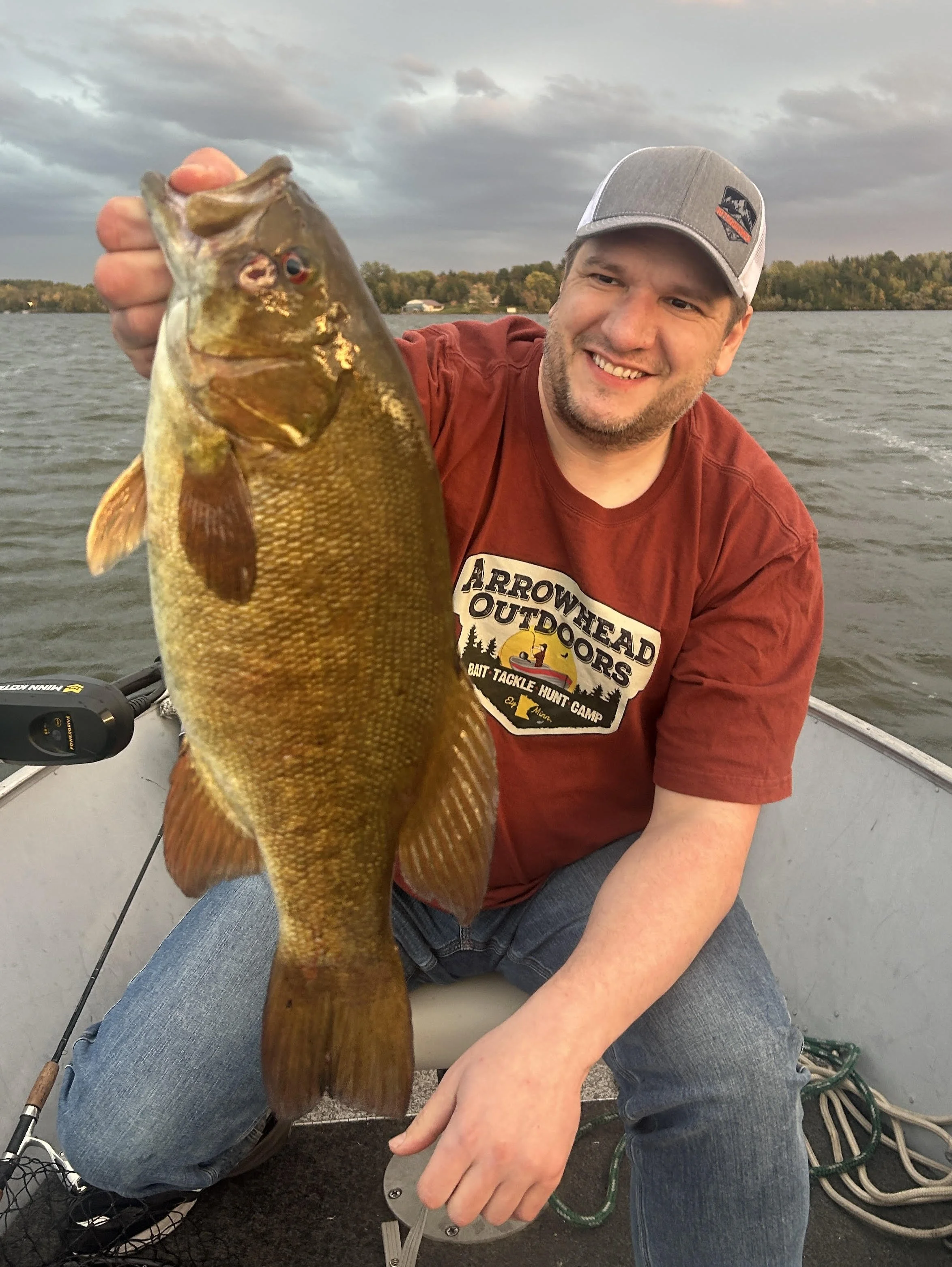 Angler holds trophy smallmouth bass on heavy suckers in boat Ely MN, BWCA area, October 1 2024. Arrowhead Outdoors Ely MN fishing report with premium tackle, hunting gear & camping supplies available.
