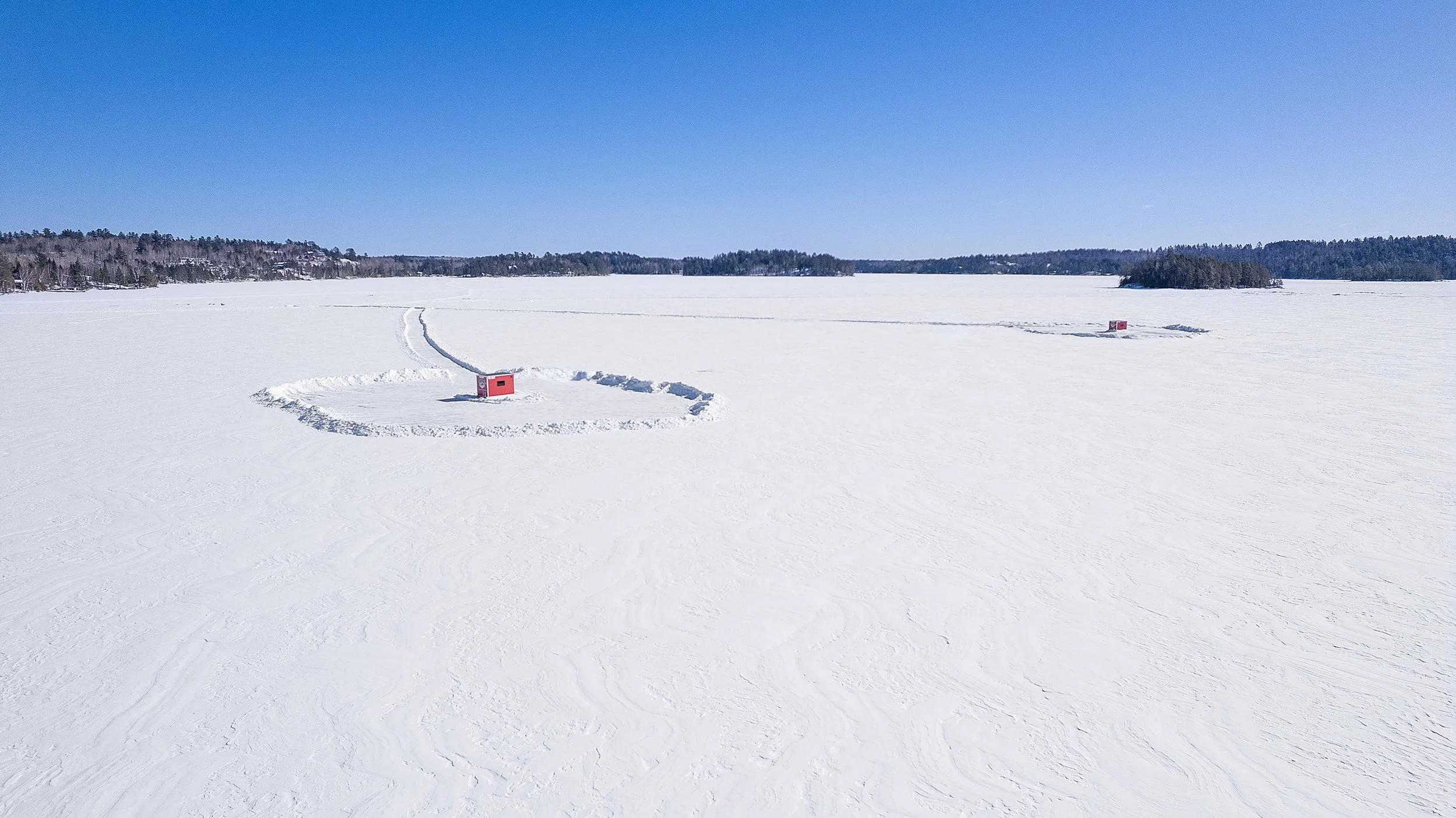 Aerial view of Arrowhead Outdoors heated ice house rentals on frozen lake near Ely MN BWCA – cozy propane-heated day-use shacks for walleye, pike, lake trout & more. Voted #1 bait shop in MN – book now!