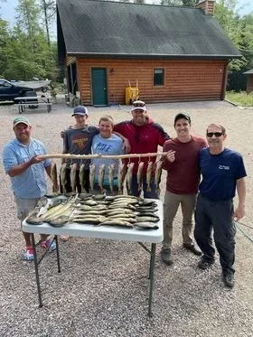 Ely MN BWCA walleye catch in Arrowhead Outdoors fishing report June 21 2021 – group of anglers with stringer of walleye by cabin