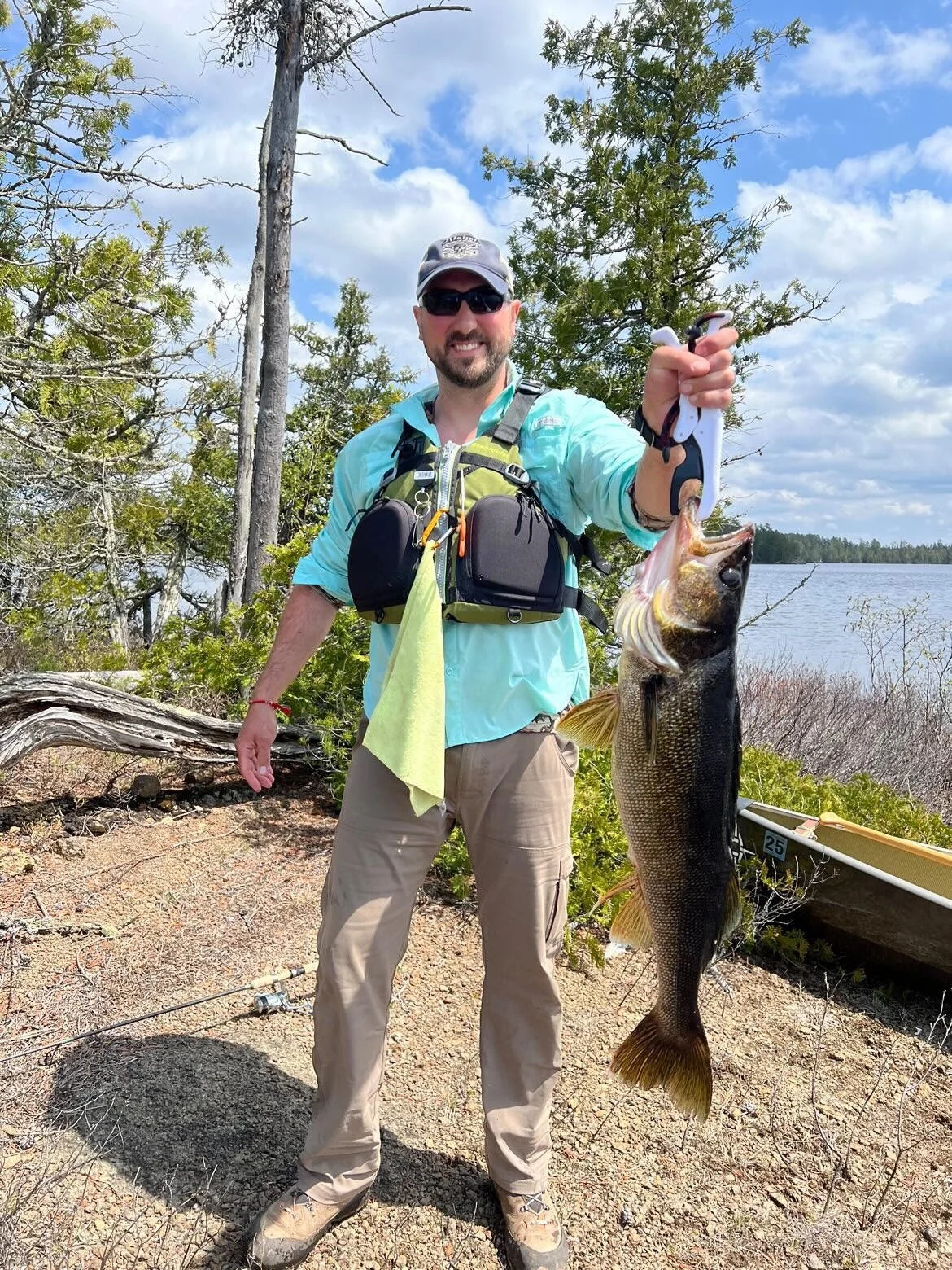 Angler holds giant 32 inch walleye on rocky shore Ely MN, BWCA area, May 21 2024. Arrowhead Outdoors Ely MN fishing report with premium tackle, hunting gear & camping supplies available.