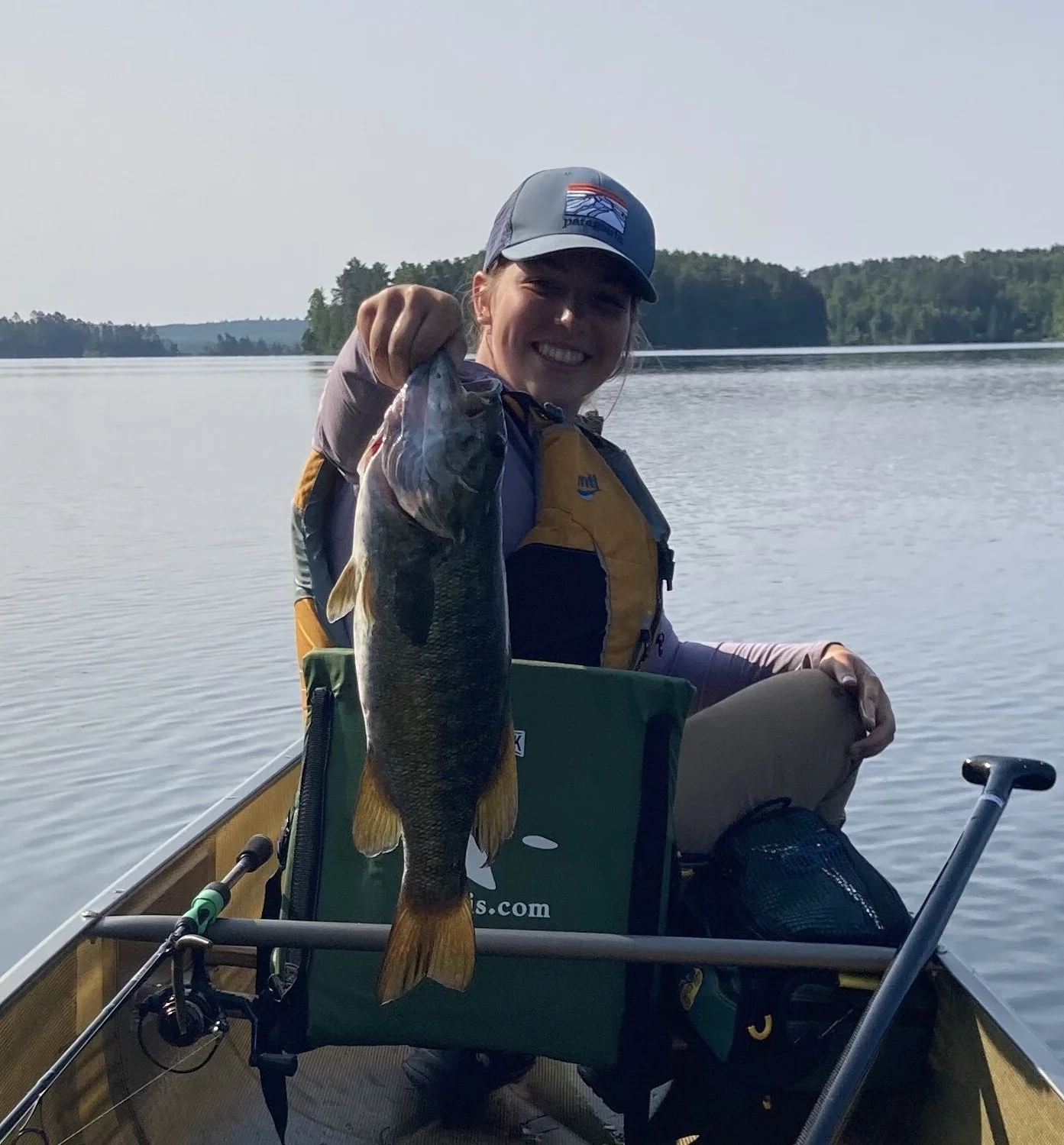 Ely MN BWCA smallmouth bass catch in Arrowhead Outdoors fishing report June 20 2023 – young angler holding bronze smallmouth in canoe sunny lake