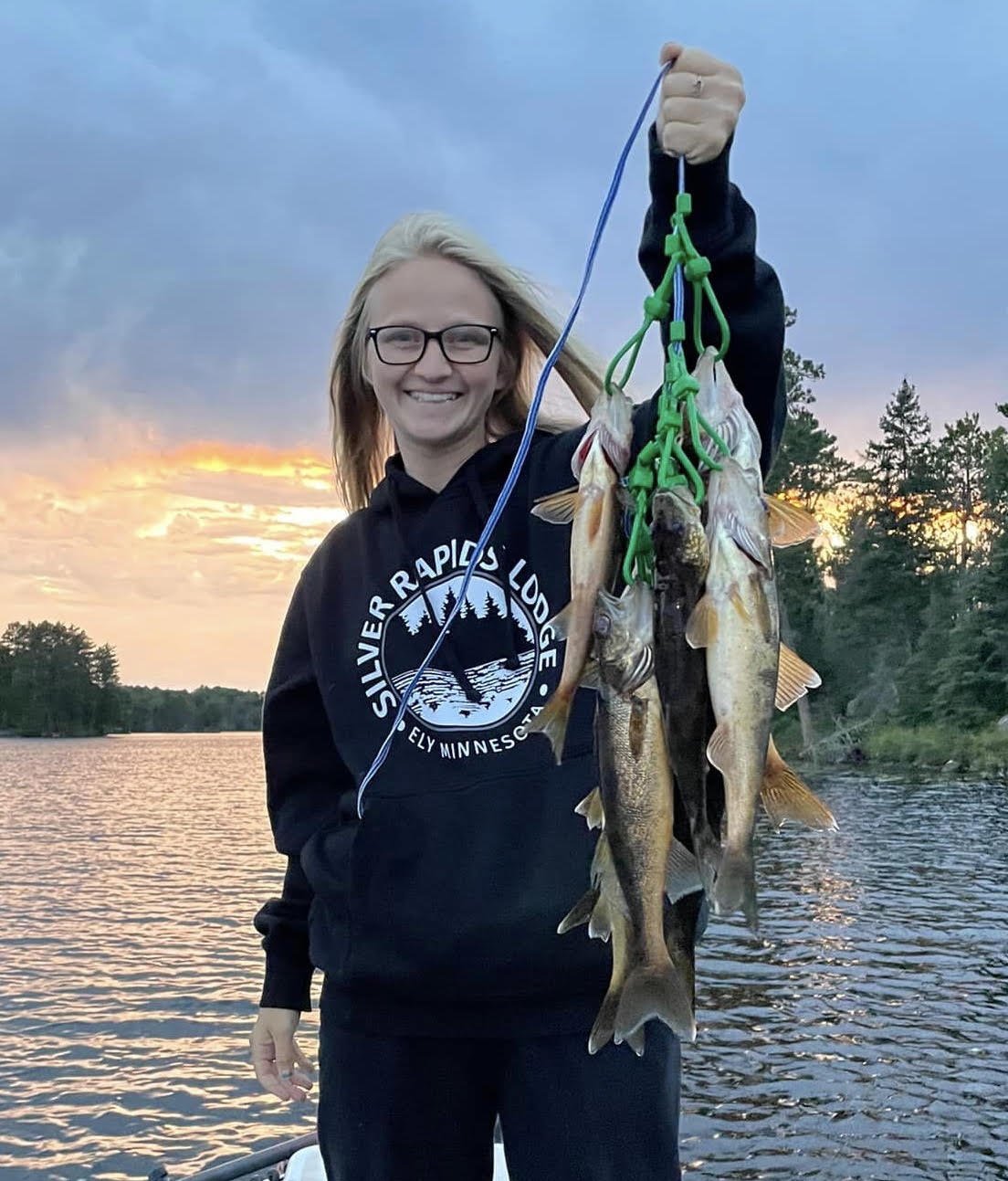 Happy angler holds walleye stringer at sunset on boat in Ely MN lake, BWCA area, September 6 2023. Arrowhead Outdoors Ely MN fishing report with premium tackle, hunting gear & camping supplies in stock.