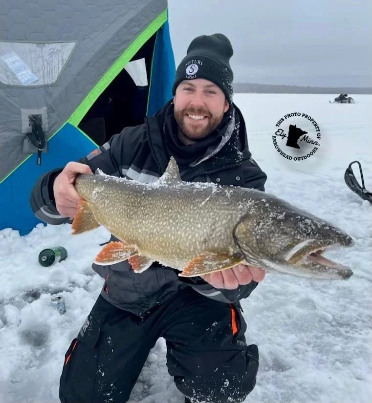 Angler with lake trout on ice Ely MN BWCA from Arrowhead Outdoors January 25 2022 fishing report post-opener slowdown few trout daily graphing marks picky bite incidental pike solid ice snowy Northwoods scene