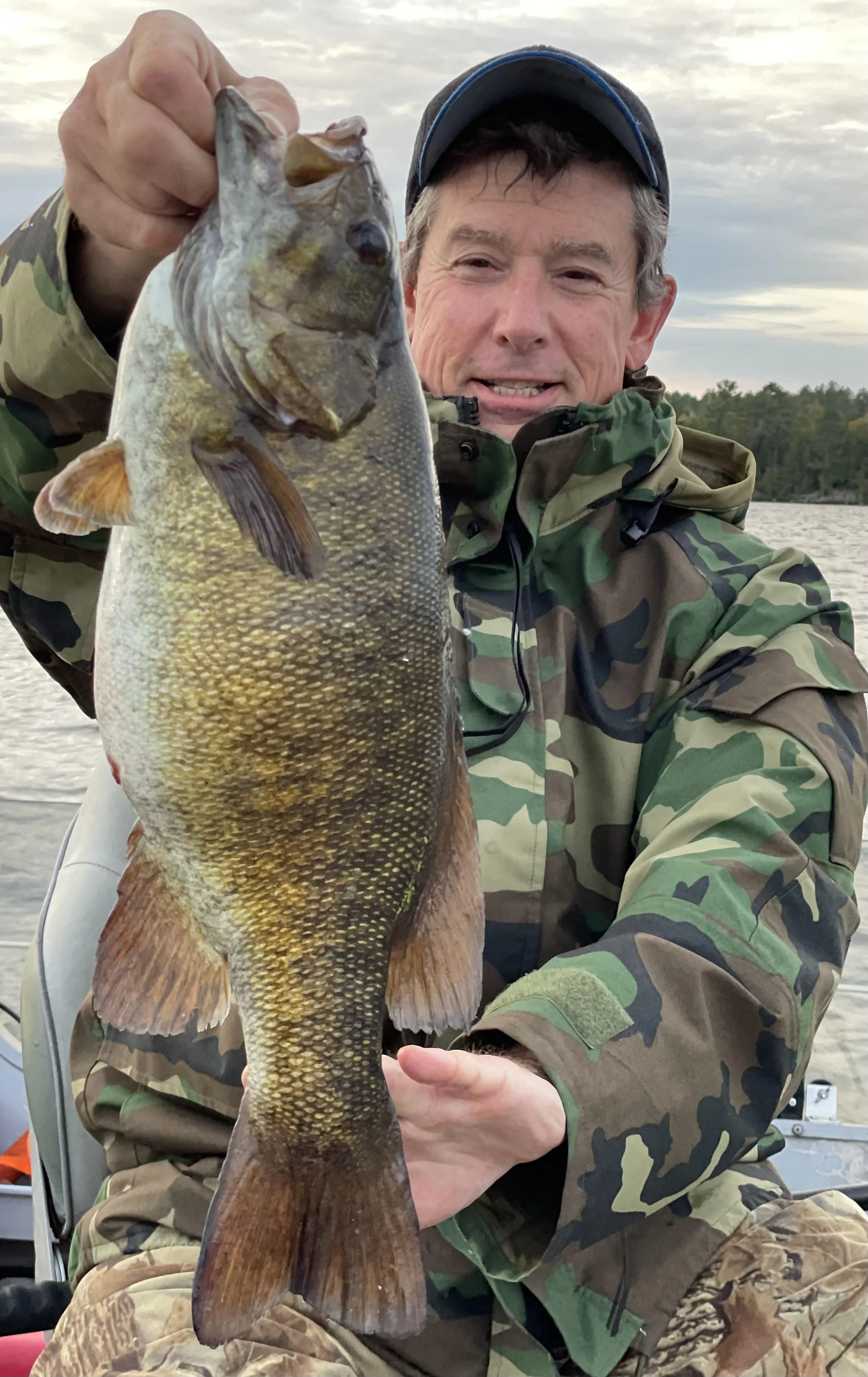 Angler holds trophy smallmouth bass on heavy suckers in boat Ely MN, BWCA area, October 6 2024. Arrowhead Outdoors Ely MN fishing report with premium tackle, hunting gear & camping supplies available.