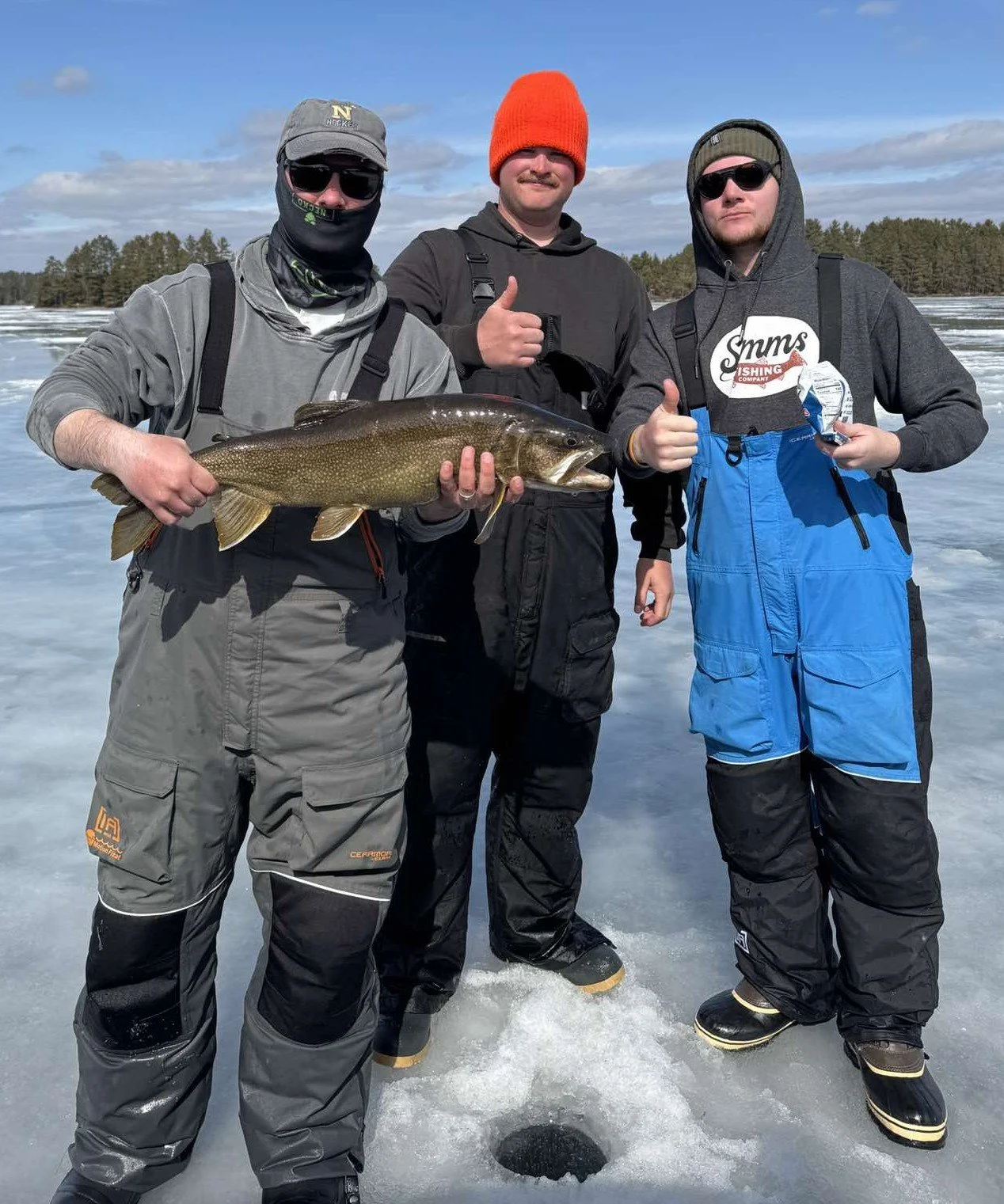 Three anglers hold lake trout on ice March 24 2026 in Ely MN BWCA. Sunny late winter fishing report from Arrowhead Outdoors.