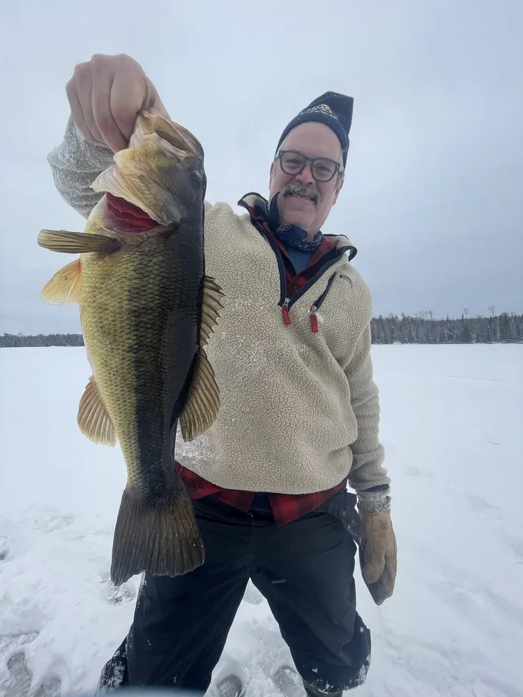 Ely MN BWCA largemouth bass ice fishing catch Mar 2 2021, angler holding green-gold largemouth on snowy frozen lake, Arrowhead Outdoors report