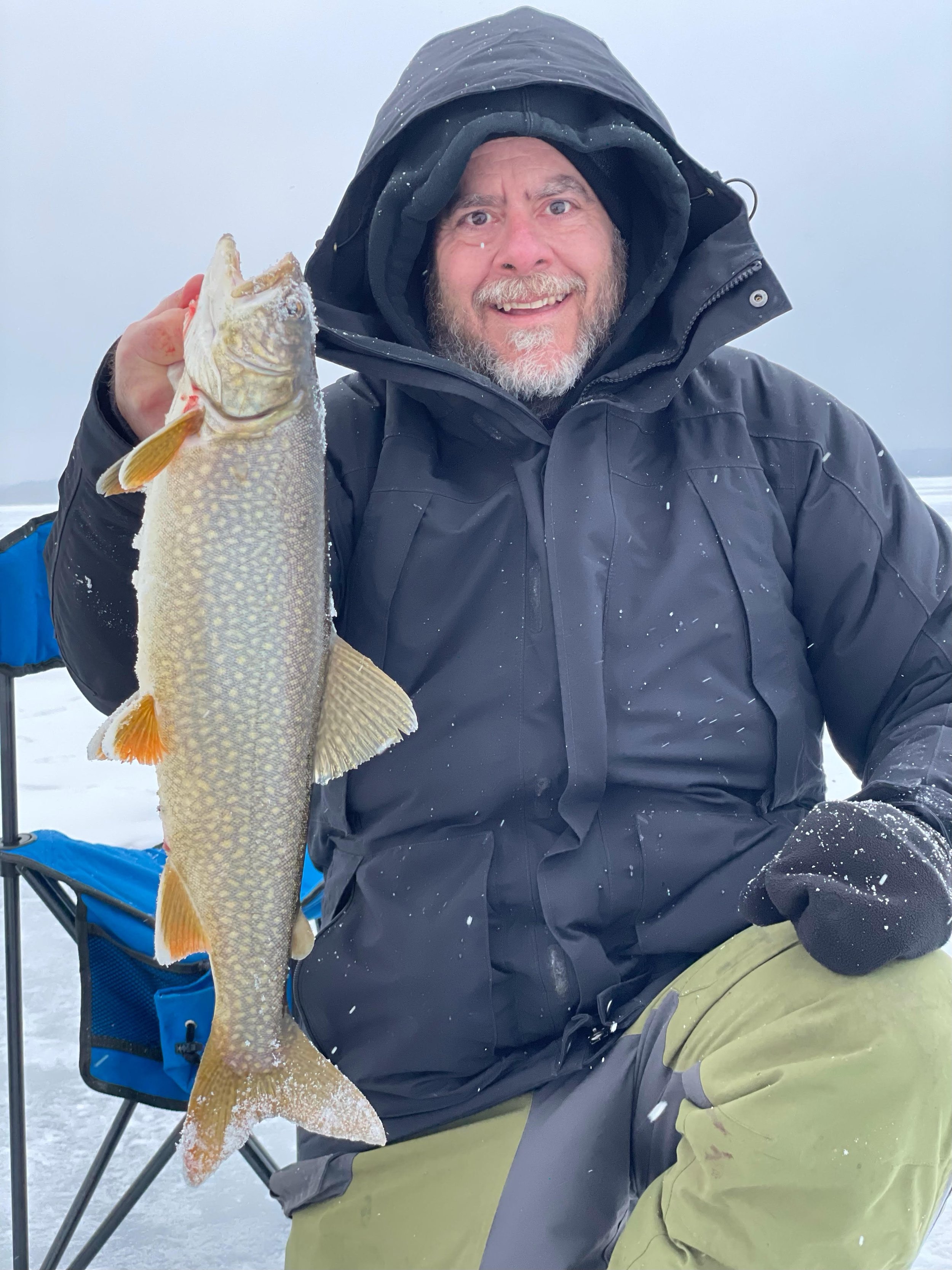 Angler holds lake trout caught on Laker Tackle tube on snowy ice in Ely MN, BWCA area, February 20 2024. Arrowhead Outdoors Ely MN winter fishing report with ice house rentals, premium tackle, hunting gear & camping supplies.