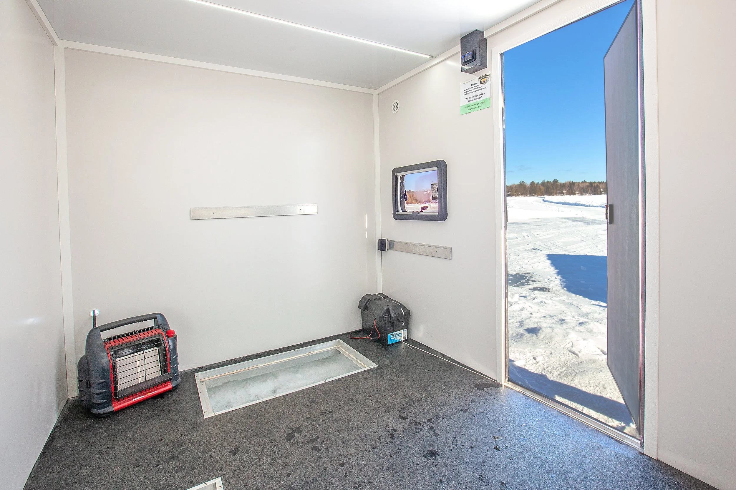 Inside view of Arrowhead Outdoors heated ice house rental near Ely MN BWCA – cozy propane heat, LED lights, bench & floor hatch for walleye, pike, lake trout & more. Voted #1 bait shop in MN – book your day-use shack now!