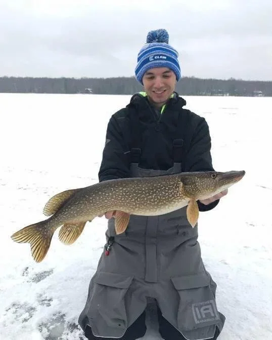 Ely MN BWCA northern pike catch in Arrowhead Outdoors fishing report January 24 2023 – angler holding big toothy pike on snowy ice BWCA lake
