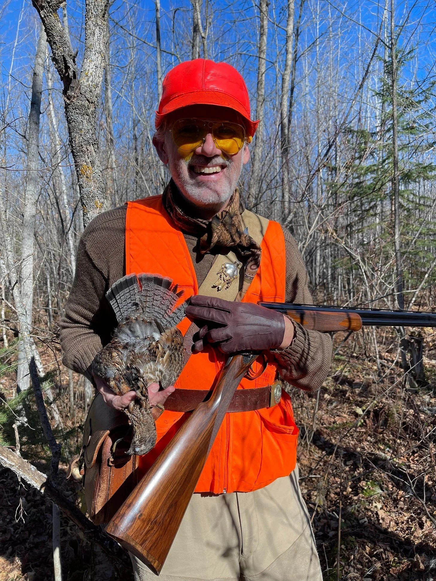 Hunter holds ruffed grouse in fall woods near Ely MN BWCA. Classic Northwoods grouse hunt from Arrowhead Outdoors.