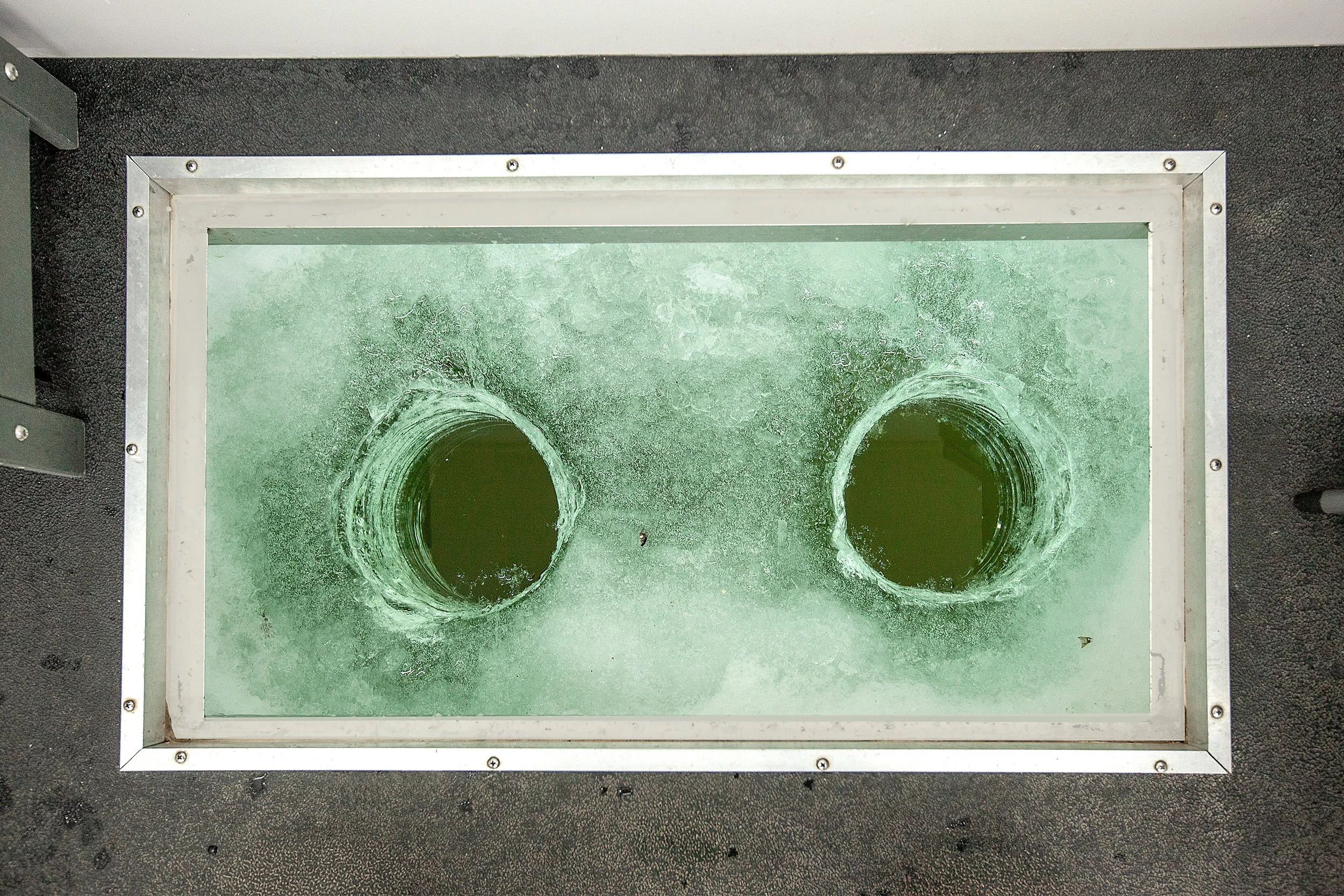 Inside view of Arrowhead Outdoors heated ice house rental near Ely MN BWCA – wide floor hatches, propane heat & LED lights for walleye, pike, lake trout & more. Voted #1 bait shop in MN – book your day-use unit now!