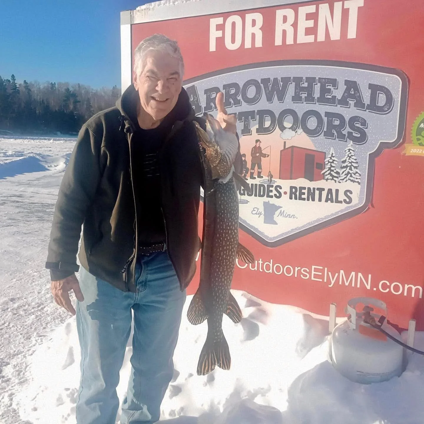 Angler holding trophy northern pike caught ice fishing in Ely MN at Arrowhead Outdoors rental shack, February 2026.