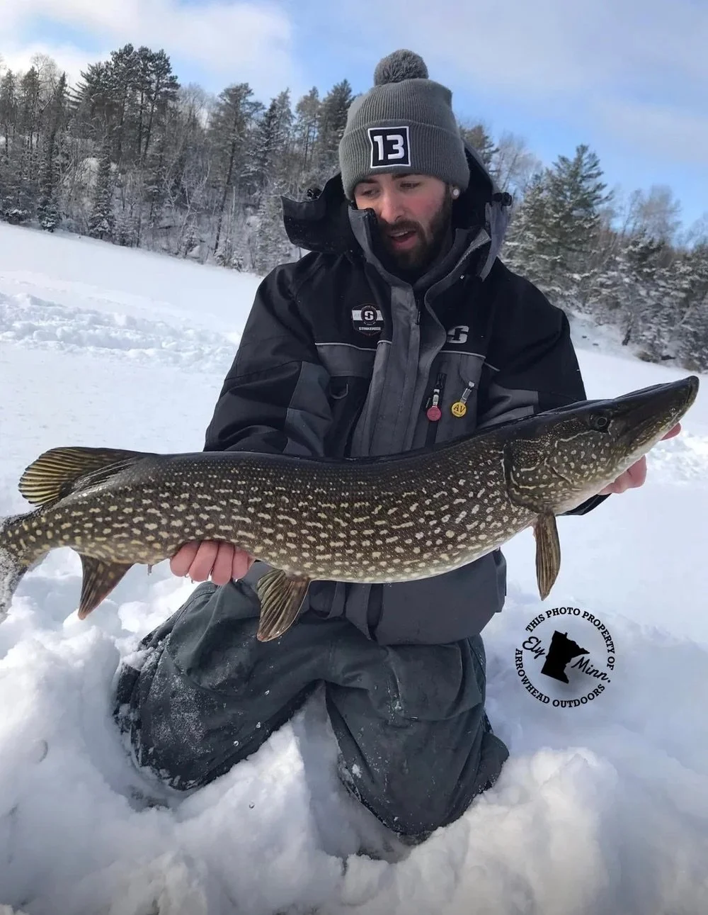 Ely MN BWCA northern pike ice fishing catch Dec 8 2021, angler holding big spotted pike on snowy ice under cloudy sky, Arrowhead Outdoors report