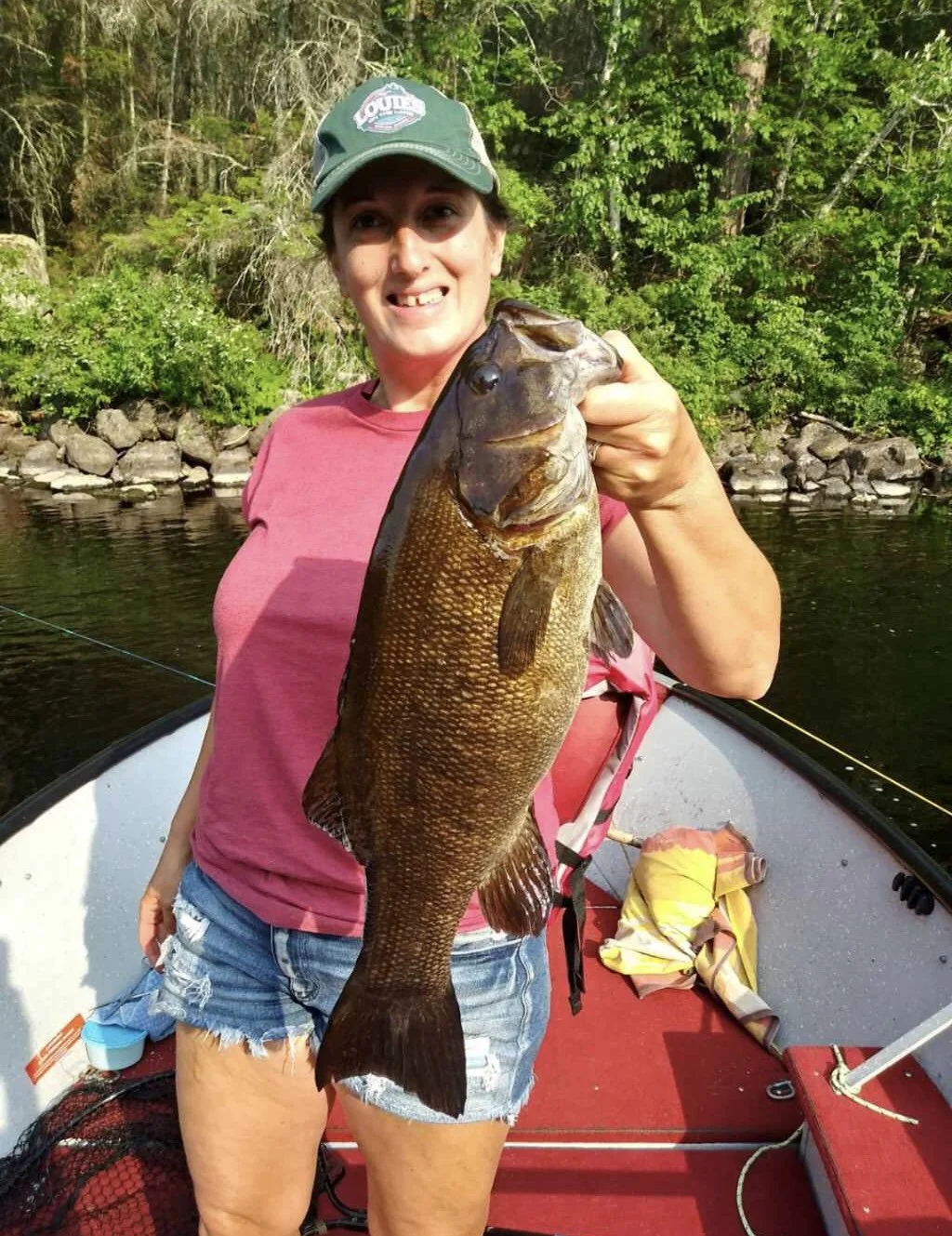 Ely MN BWCA smallmouth bass catch in Arrowhead Outdoors fishing report August 8 2023 – angler holding bronze smallmouth on boat sunny lake