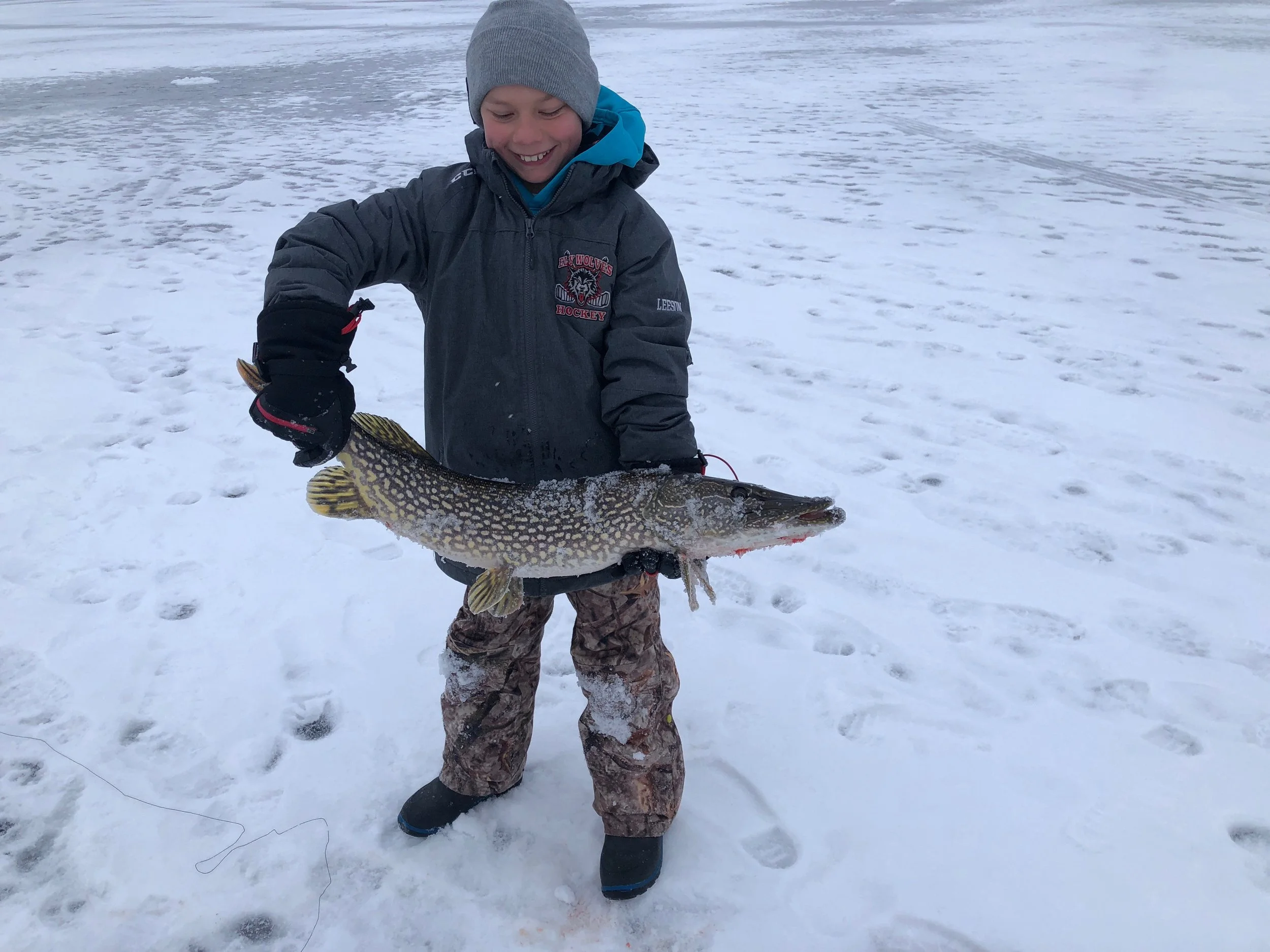 Young angler holds northern pike on ice in Ely MN BWCA - Arrowhead Outdoors December 2 2020 fishing report