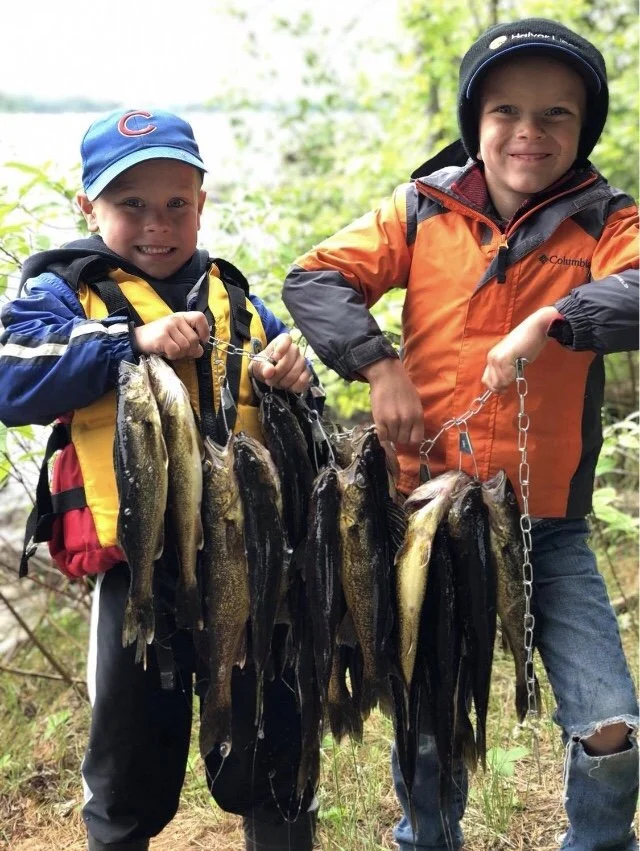 Kids with huge walleye stringer caught near Ely MN using bait from Arrowhead Outdoors – best BWCA family fishing trip