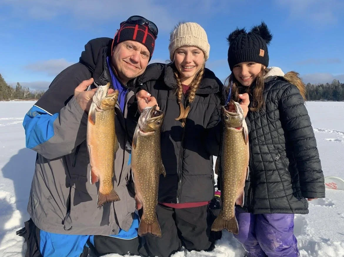 Family holds trophy brook trout on ice after catching with Cast Outdoor Adventures January 15, 2025 in Ely MN BWCA. Winter stream trout report from Arrowhead Outdoors.