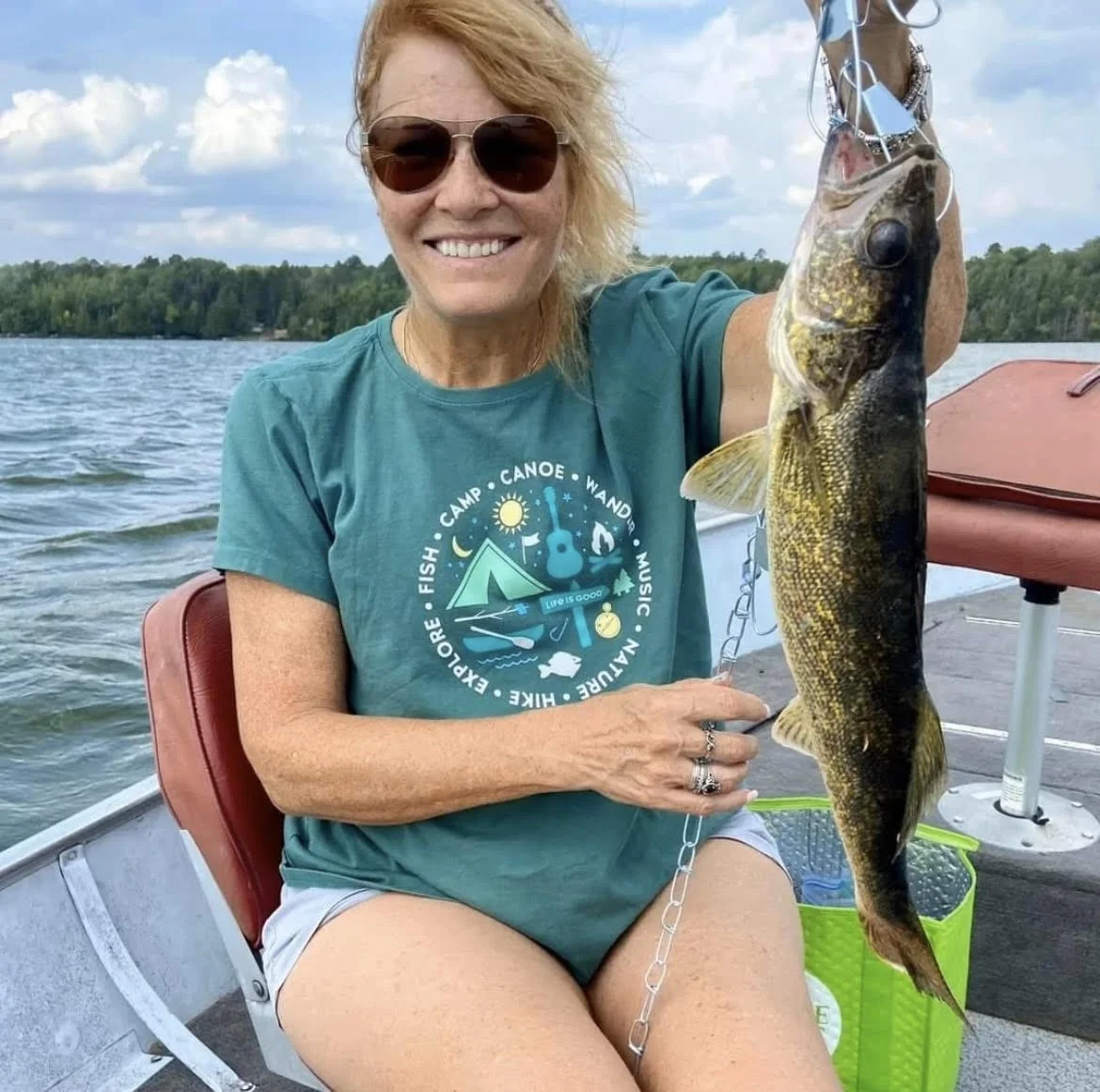 Smiling angler holds fresh walleye on stringer in boat on sunny Ely MN lake, BWCA area, September 13 2023. Arrowhead Outdoors Ely MN fishing report with premium tackle, hunting gear & camping supplies available.