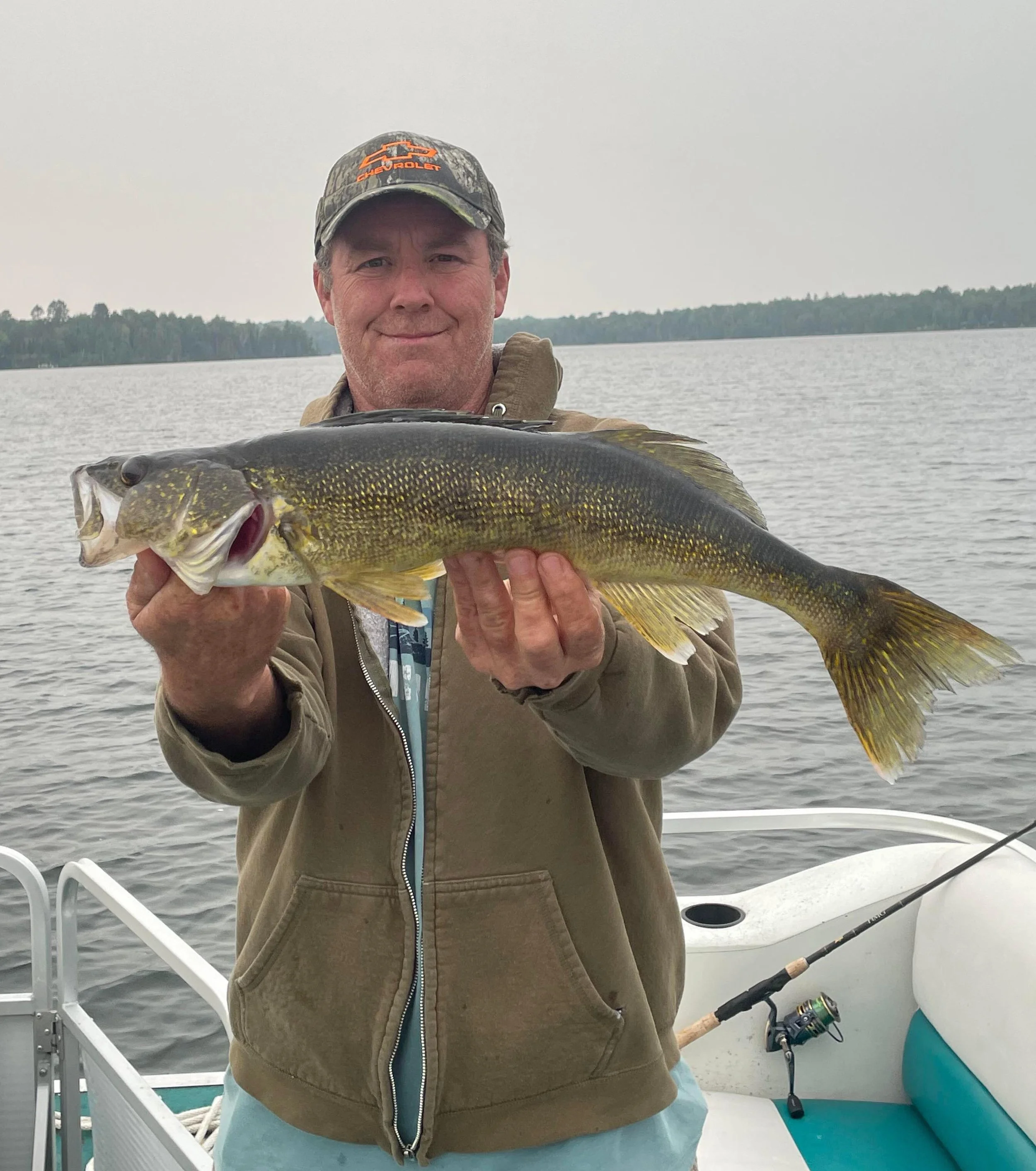 Ely MN BWCA walleye catch in Arrowhead Outdoors fishing report July 27 2023 – angler holding golden walleye on boat calm lake