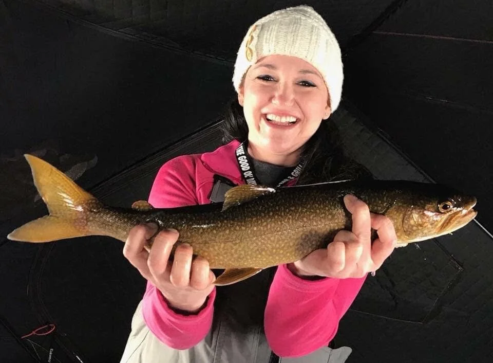 Angler holds late season lake trout on Laker Tackle Tube Jig inside ice shack March 26, 2025 in Ely MN BWCA. Winter report from Arrowhead Outdoors